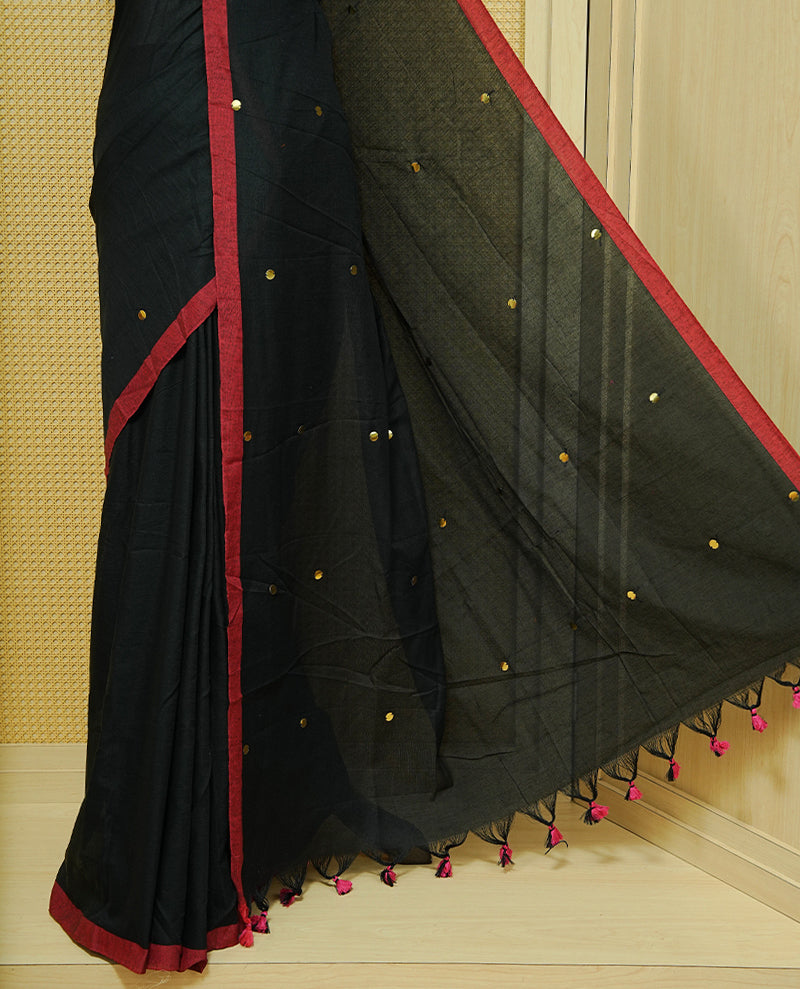 Black colour Mul cotton saree featuring Gold Sequins, complemented by Contrast Red simple Border & tassels.