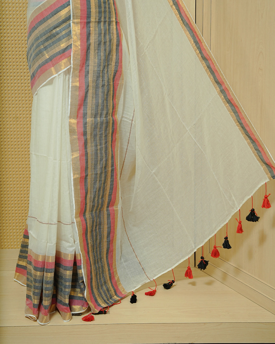 Off-White Mul Cotton Saree featuring a plain body with a multicolour striped zari border in shades of Red, Black, and gold & red and black tassels