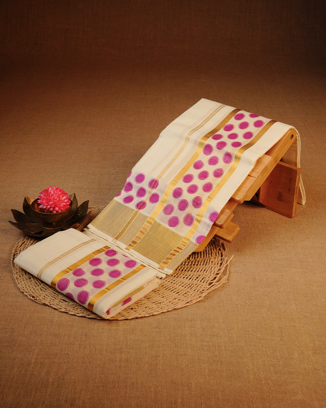 Cream colour cotton set mundu Features Plain body, Enhanced with Kasav kara with pink colour circle motifs.