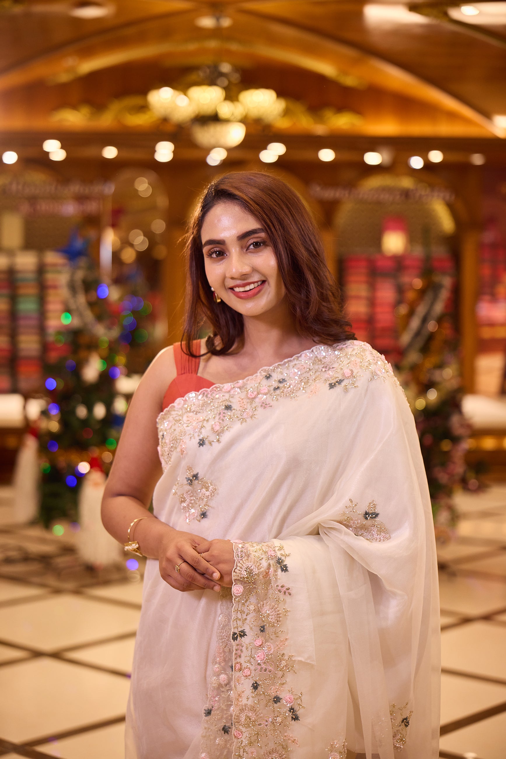 White colour Pure Organza designer saree featuring soft pastel pink and blue floral bead and sequin embroidery with a delicately scalloped embellished border, paired with a matching designer blouse.