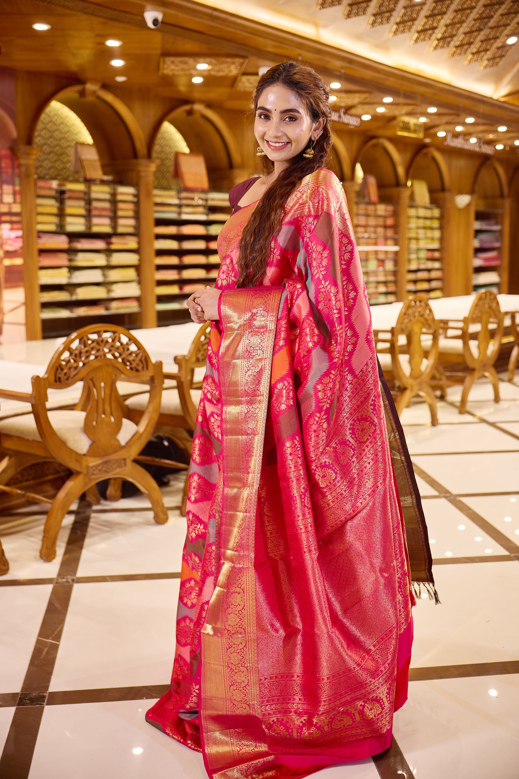Red pink dual shade Rankat Kanchipuram Samudrika Silk Saree adorned with 5 colour silk thread and golden zari wave motifs, finished with a traditional arumbu malligai mayilkan border, rich arai madam lotus pallu, and a matching self plain blouse.