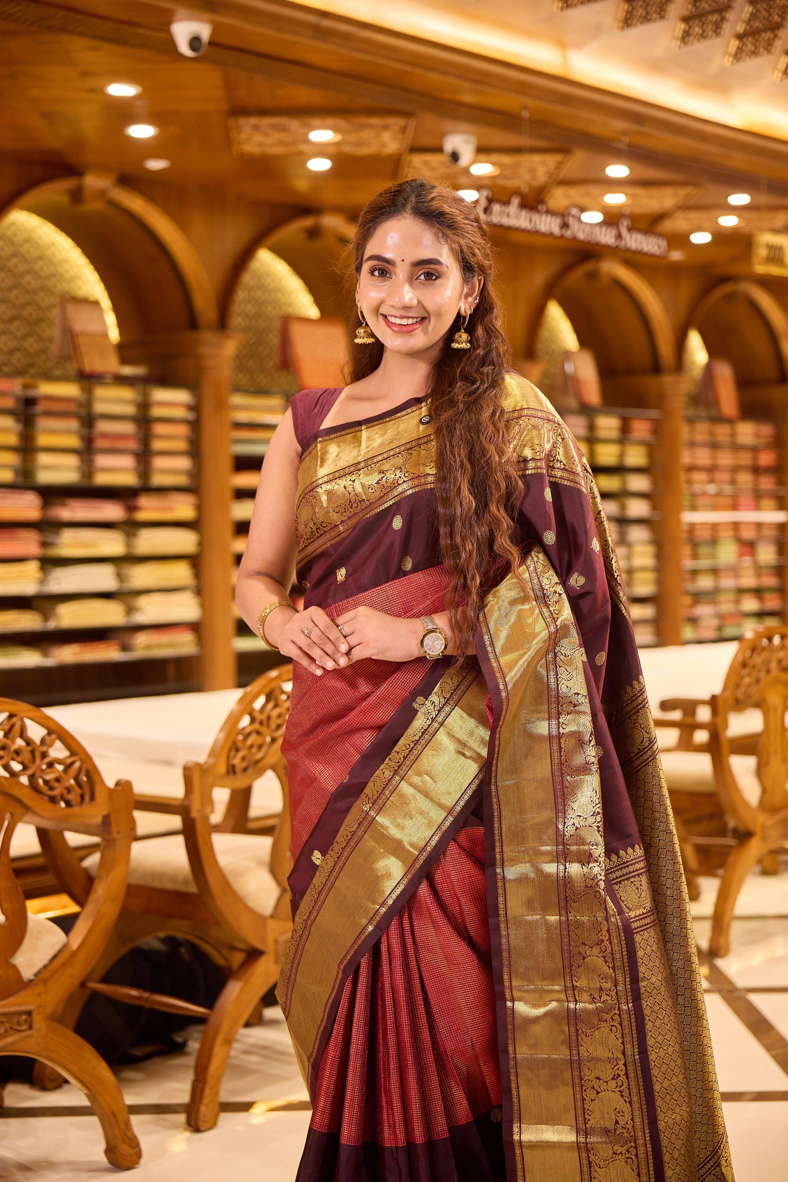 Maroon & Brown Shade Kanchipuram Traditional Handloom Silk Saree featuring vaira oosi zari checks on the body with contrasting Mayuri chakra motifs woven in rich antique gold zari, elegantly finished with a classic gold zari border.