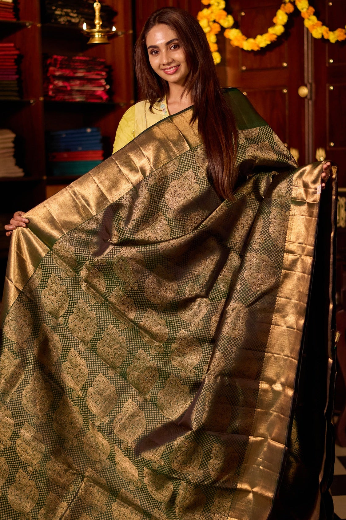 Deep green pure Kancheepuram silk saree featuring elegant gold zari Motifs, a rich gold zari pallu, and a broad gold zari border, paired with a matching blouse.