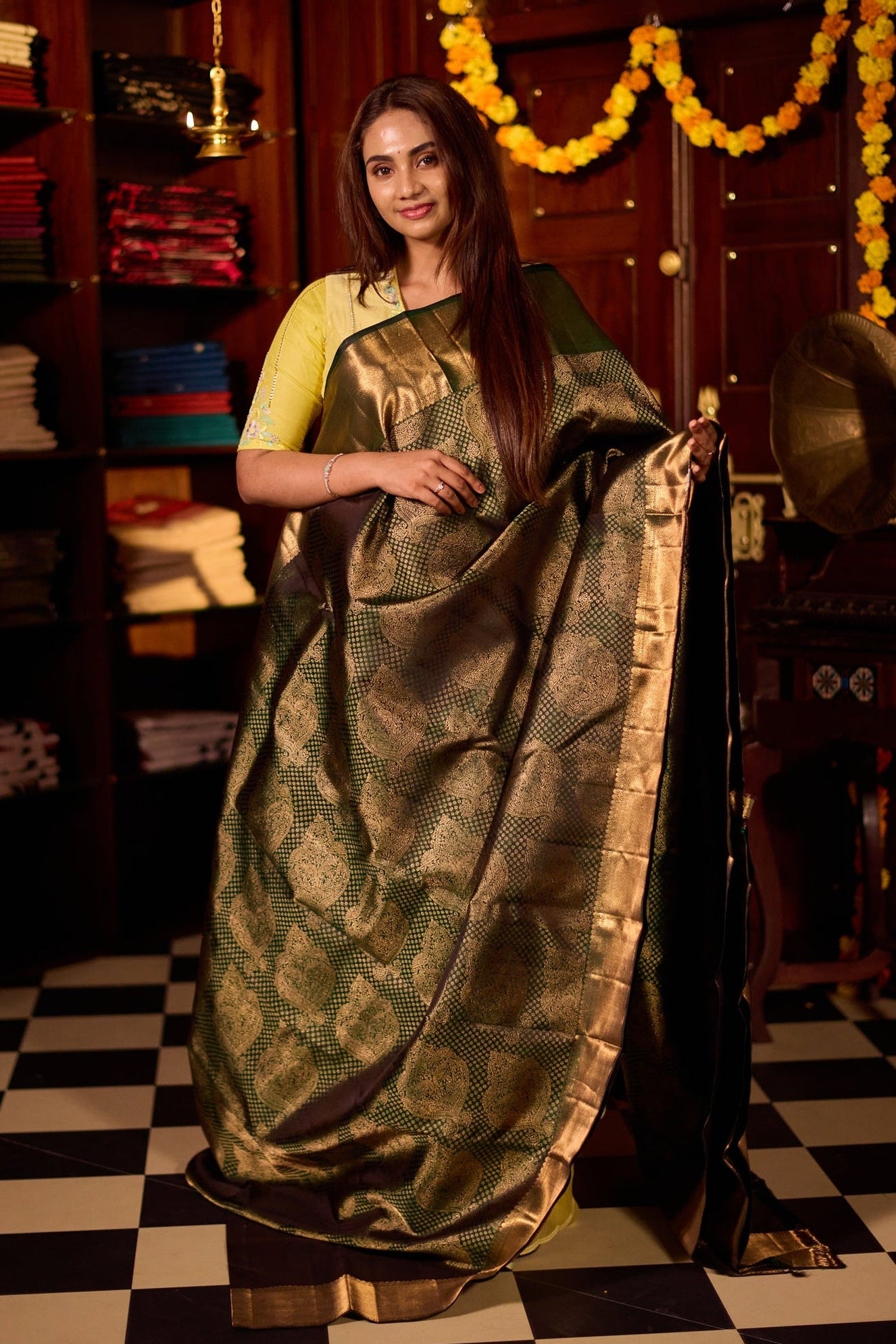 Deep green pure Kancheepuram silk saree featuring elegant gold zari Motifs, a rich gold zari pallu, and a broad gold zari border, paired with a matching blouse.
