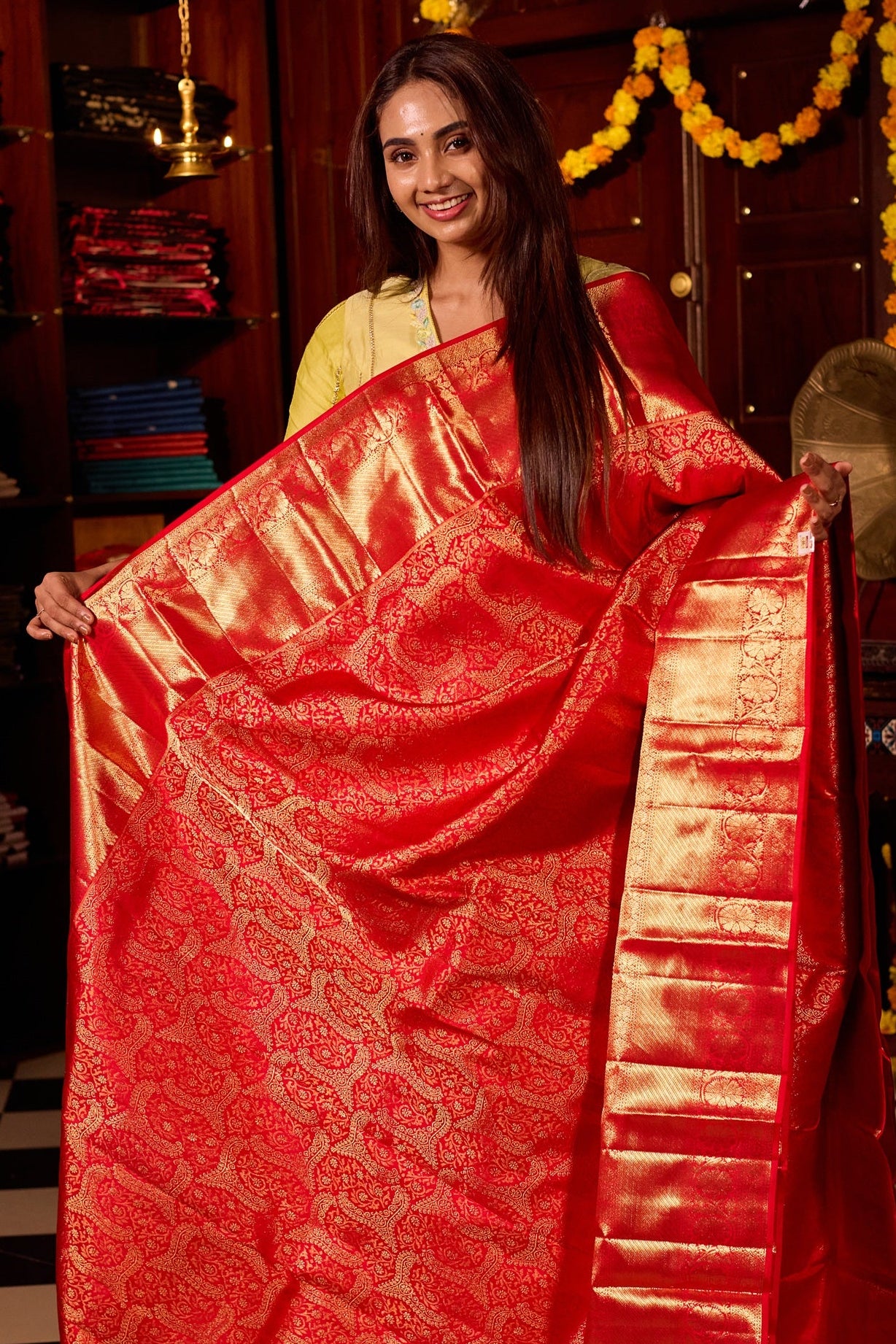 Rich red pure Kancheepuram silk saree featuring intricate gold zari weaving, a lustrous gold zari pallu, and a broad gold zari border, beautifully paired with matching blouse.