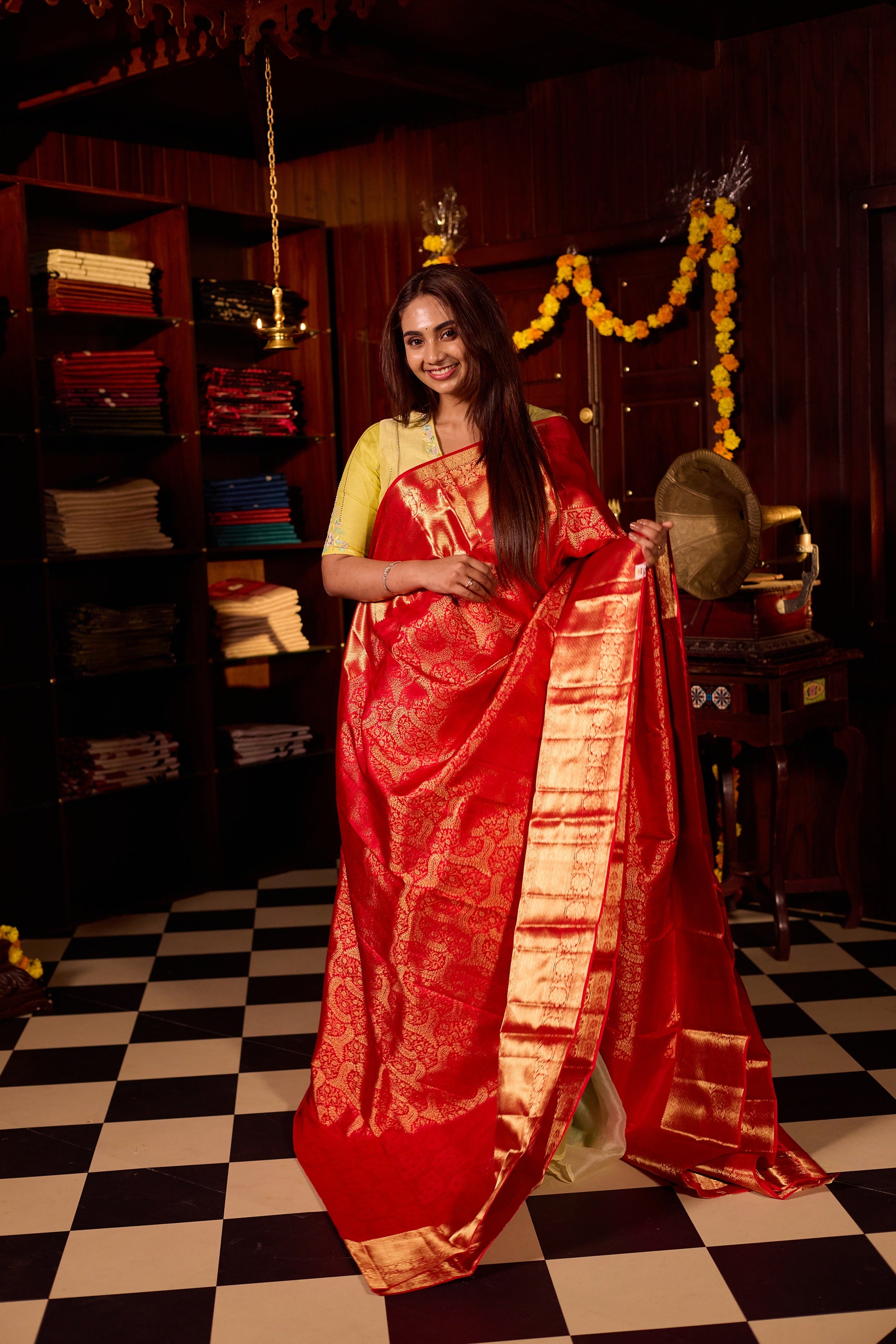 Rich red pure Kancheepuram silk saree featuring intricate gold zari weaving, a lustrous gold zari pallu, and a broad gold zari border, beautifully paired with matching blouse.