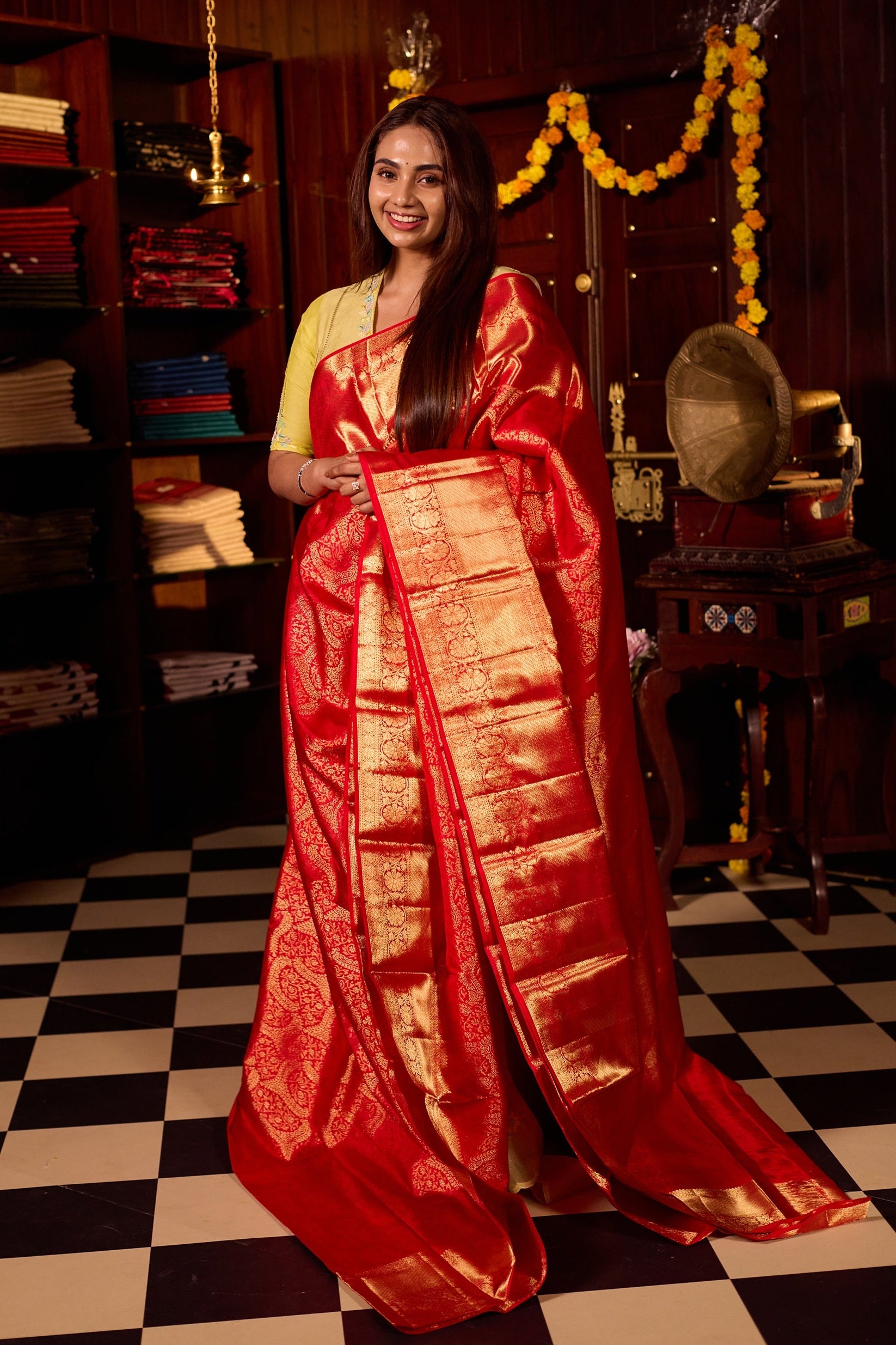 Rich red pure Kancheepuram silk saree featuring intricate gold zari weaving, a lustrous gold zari pallu, and a broad gold zari border, beautifully paired with matching blouse.