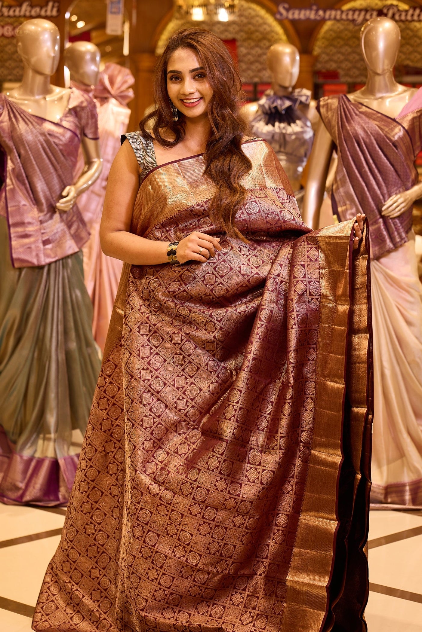 Elegant wine brown colour Kancheepuram silk saree adorned with an all over rich geometric zari weave, beautifully complemented by a broad traditional gold zari border and paired with a matching blouse piece