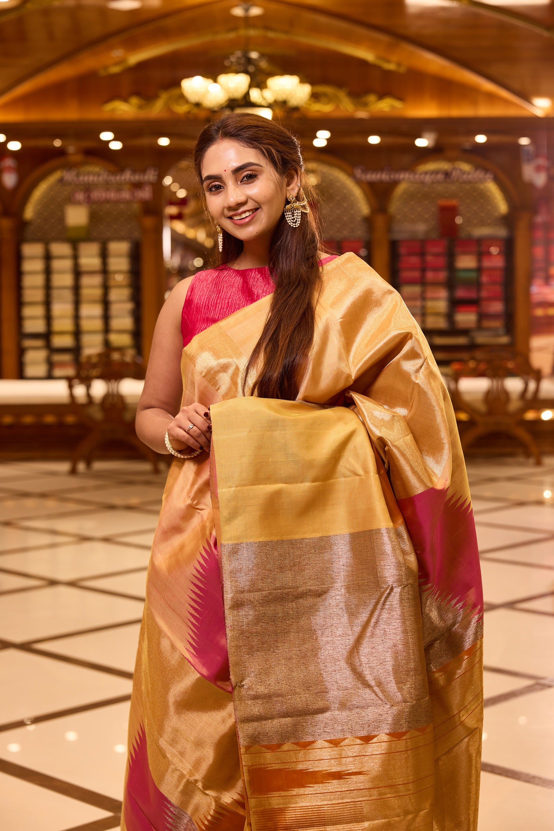Elegant golden beige colour Kancheepuram silk saree featuring subtle woven geometric highlights with soft pink accents, beautifully paired with a rich contrast pallu and styled with a vibrant blouse