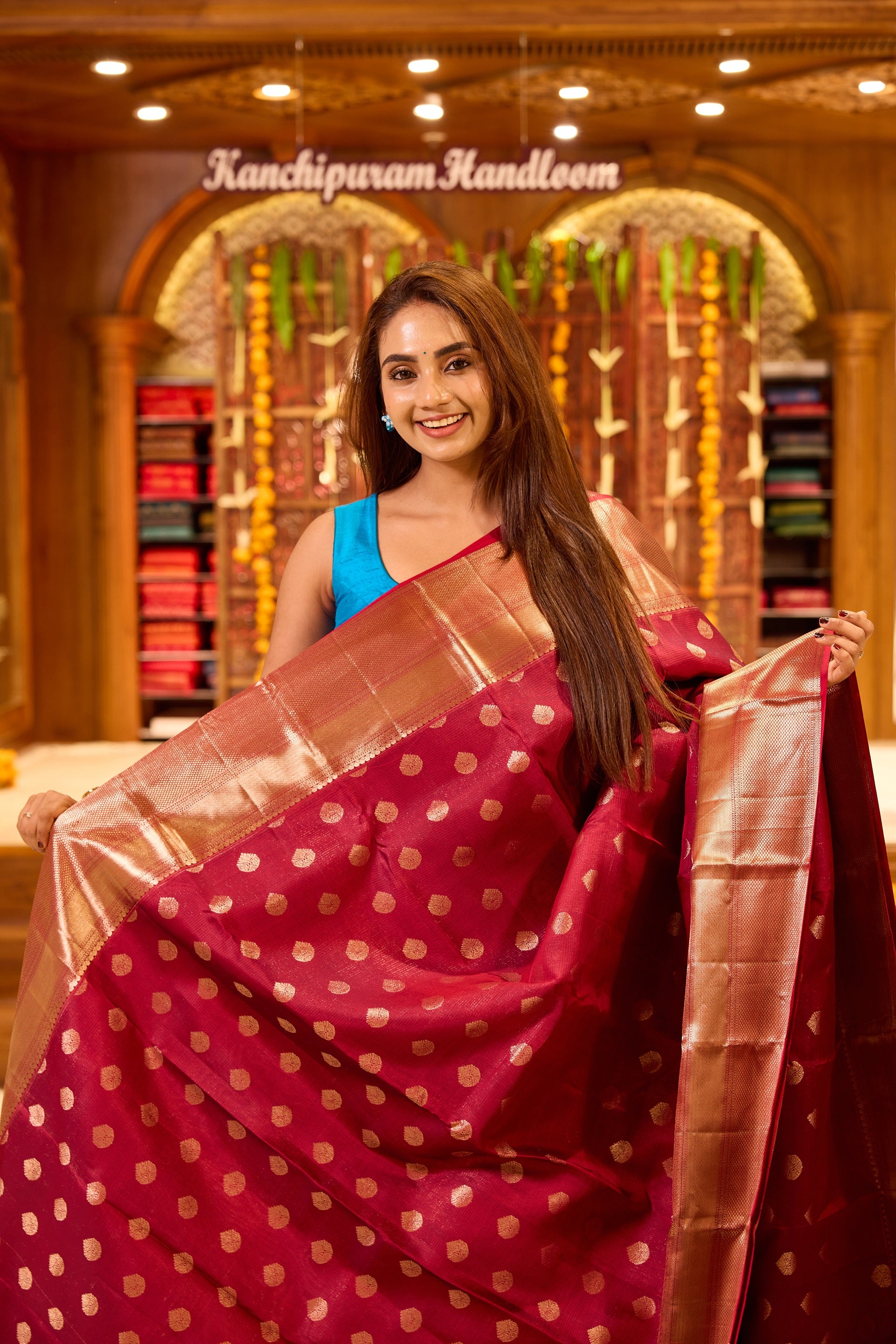 Wine colour Kancheepuram silk saree with classic gold zari polka motifs all over, complemented by a lustrous gold zari border and pallu, and paired with a matching blouse.