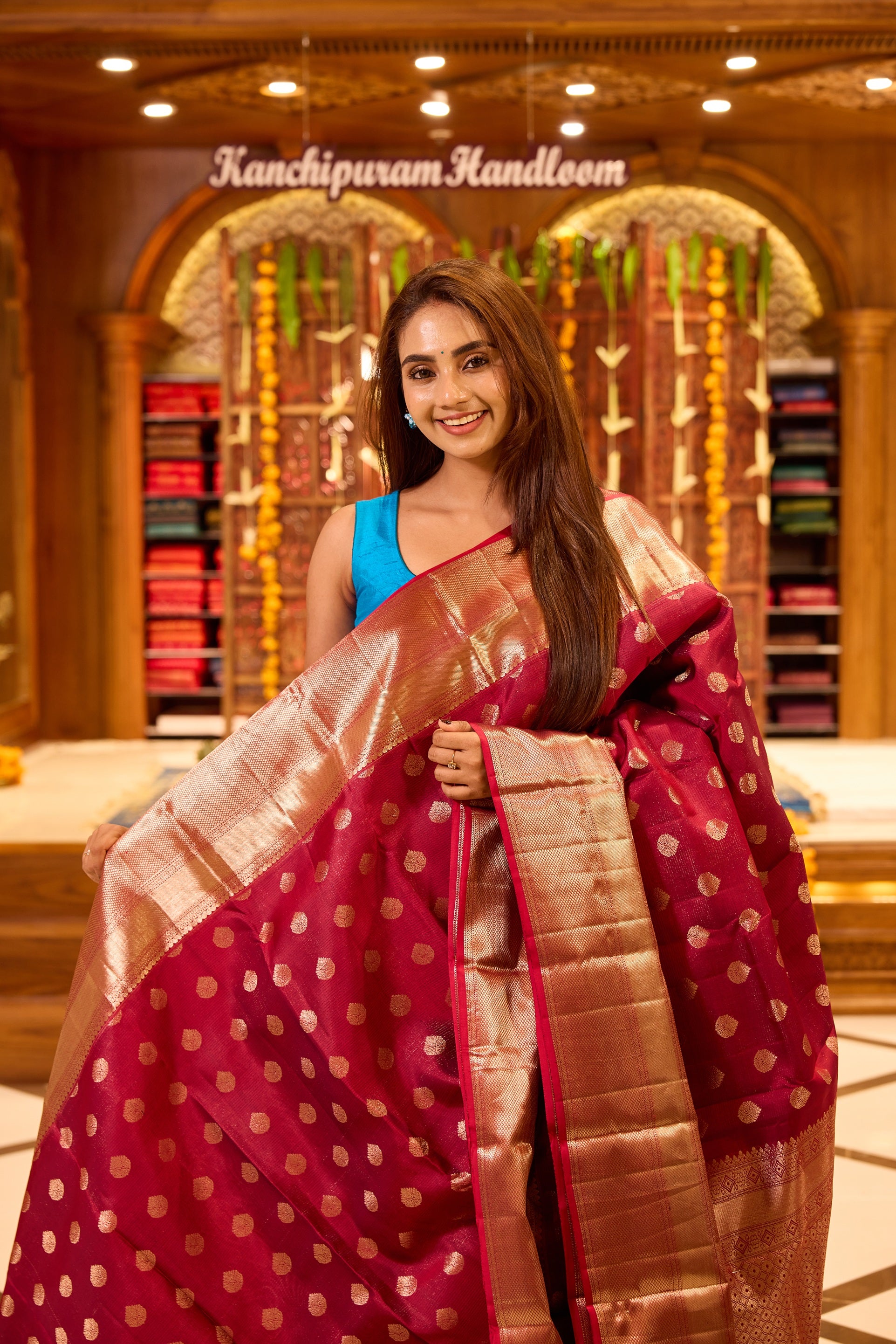 Wine colour Kancheepuram silk saree with classic gold zari polka motifs all over, complemented by a lustrous gold zari border and pallu, and paired with a matching blouse.