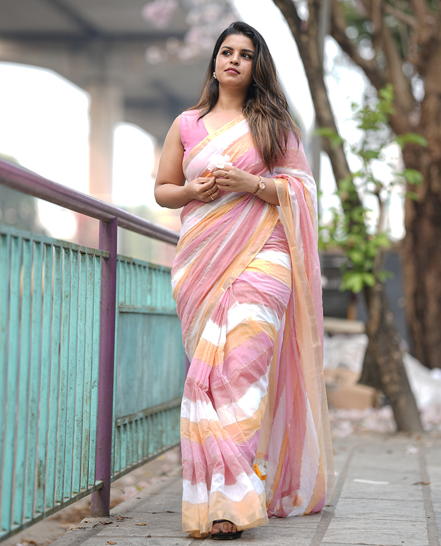 Pastel pink, yellow & white mul mul cotton saree accentuated by delicate gold borders and a subtle striped body, paired with a matching blouse piece.