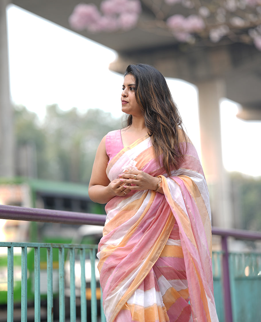 Pastel pink, yellow & white mul mul cotton saree accentuated by delicate gold borders and a subtle striped body, paired with a matching blouse piece.