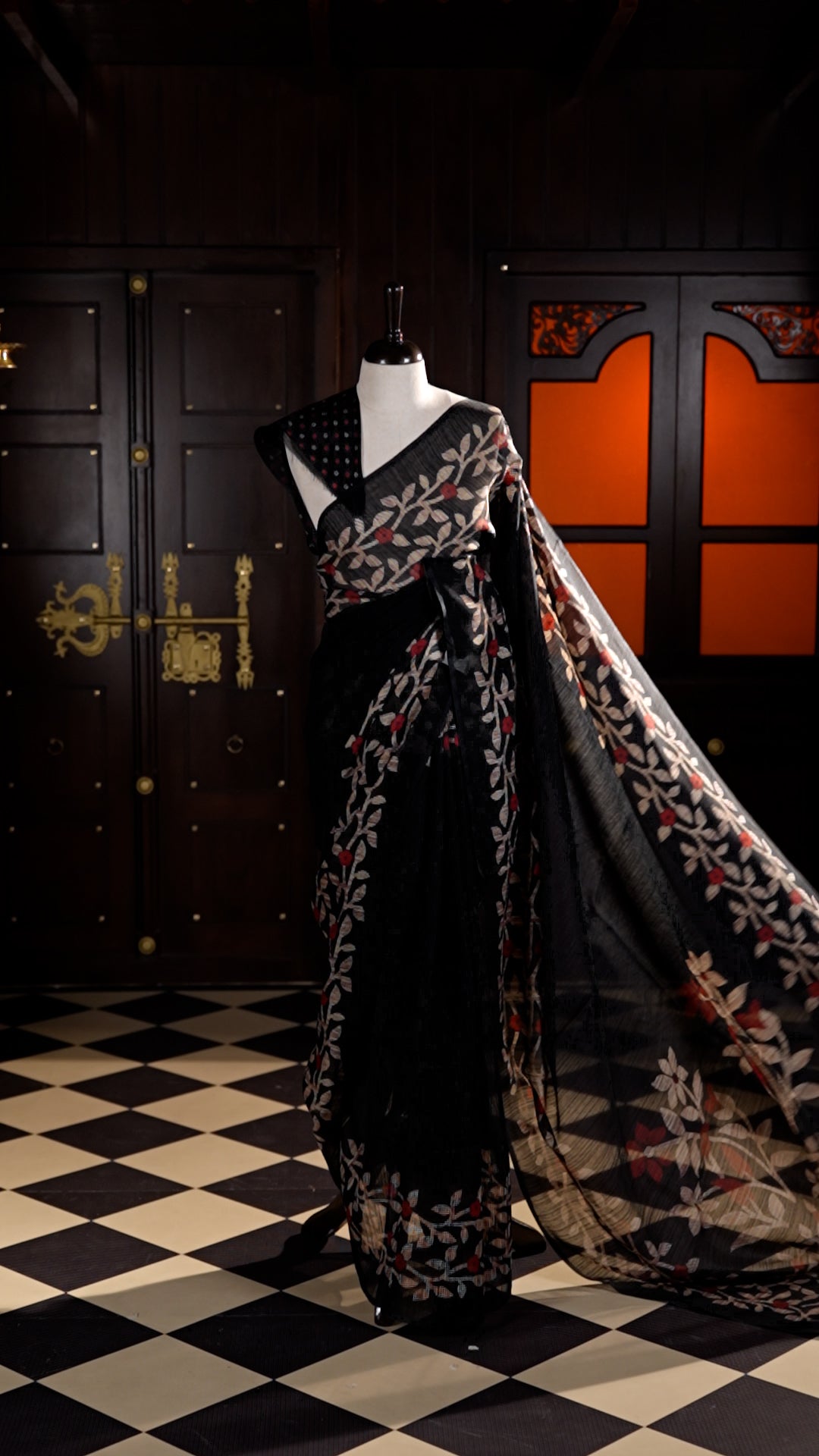Black colour Semi Jute Material saree with leaf print and floral design on body, finished with a floral designed matching blouse.