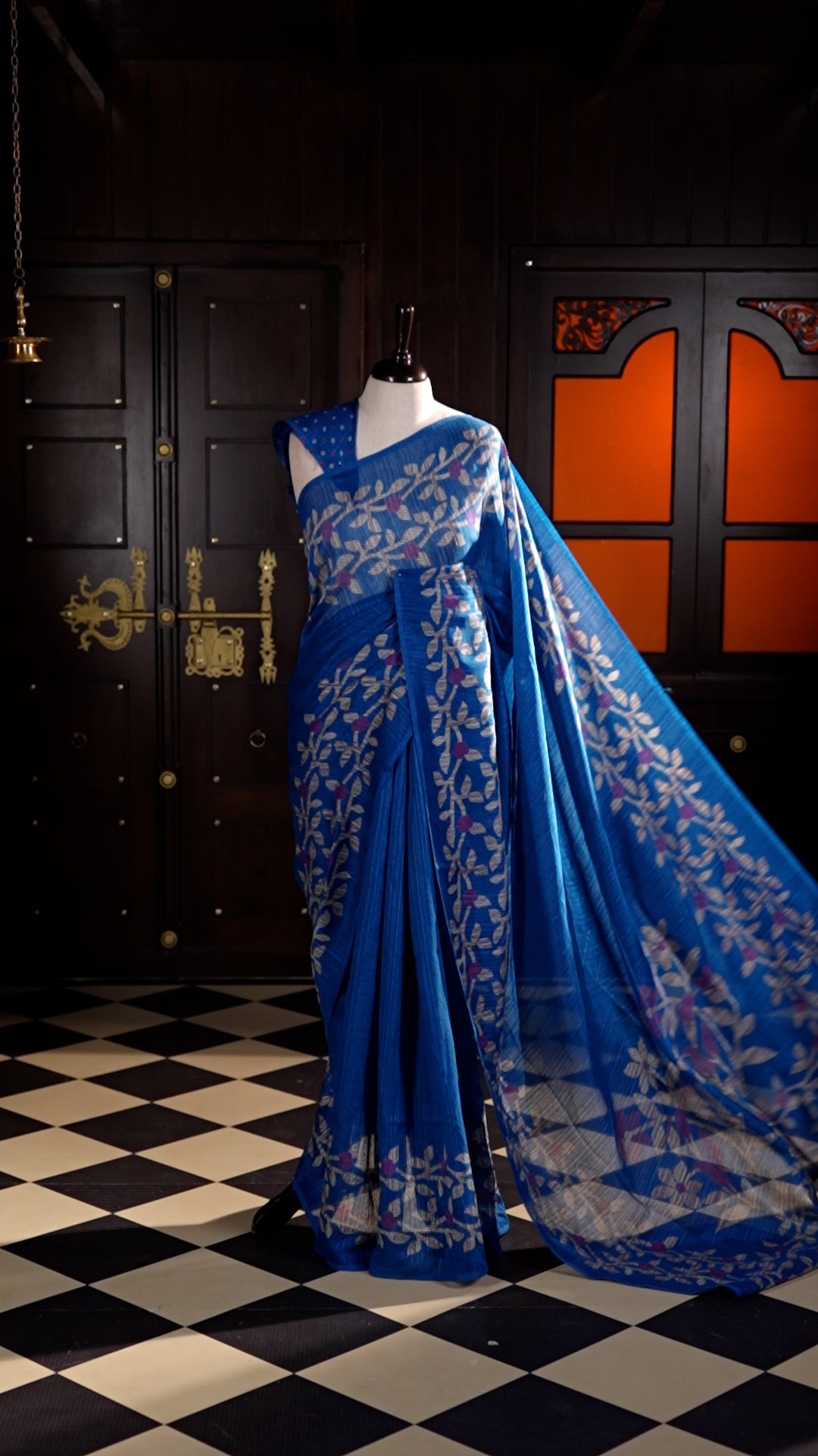 Blue colour Semi Jute Material saree with leaf print and floral design on body, finished with a floral designed matching blouse.