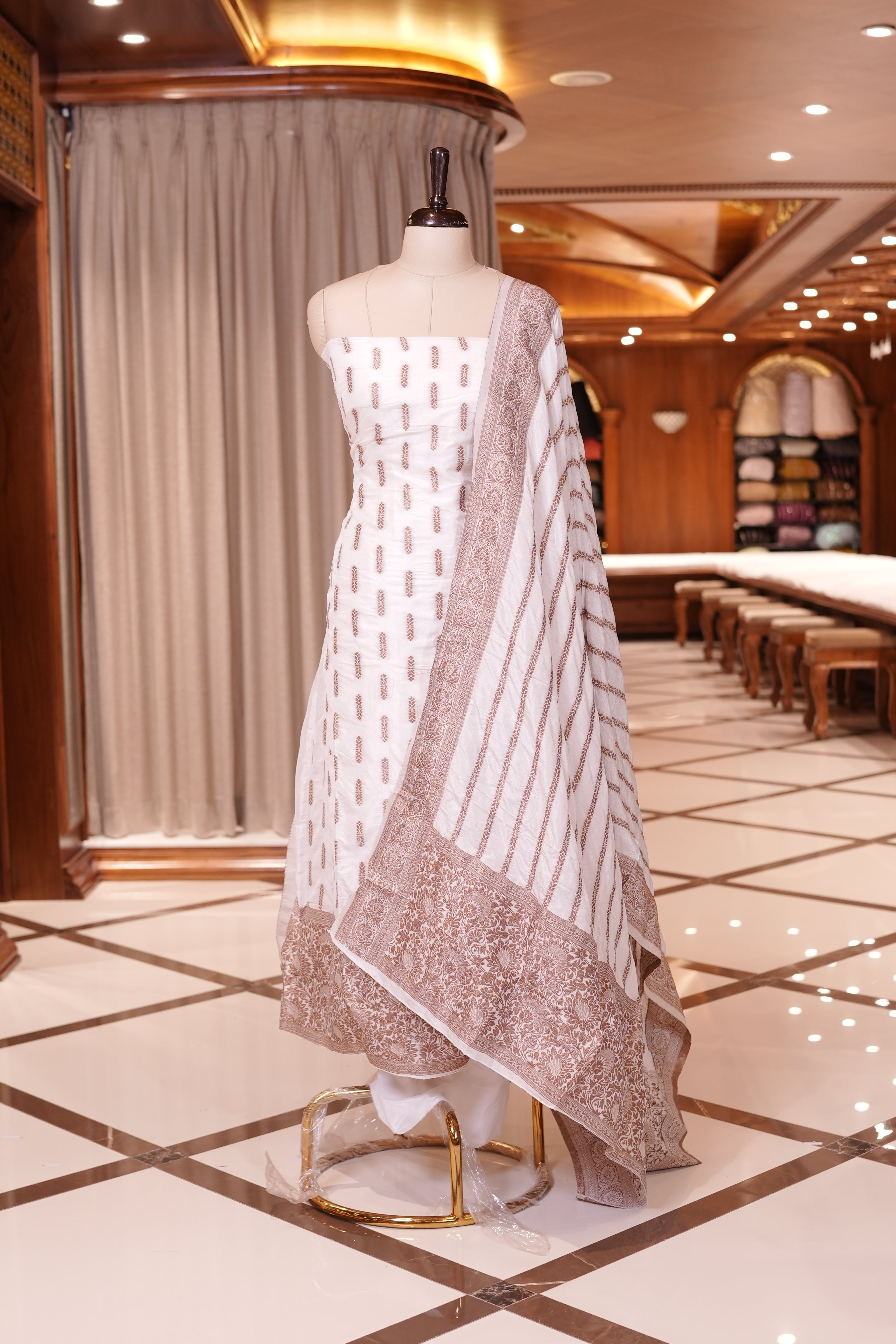 White colour Semi Banarasi Silk top adorned with elegant Copper zari patterns and a rich border, paired with a zari worked dupatta and a plain bottom.