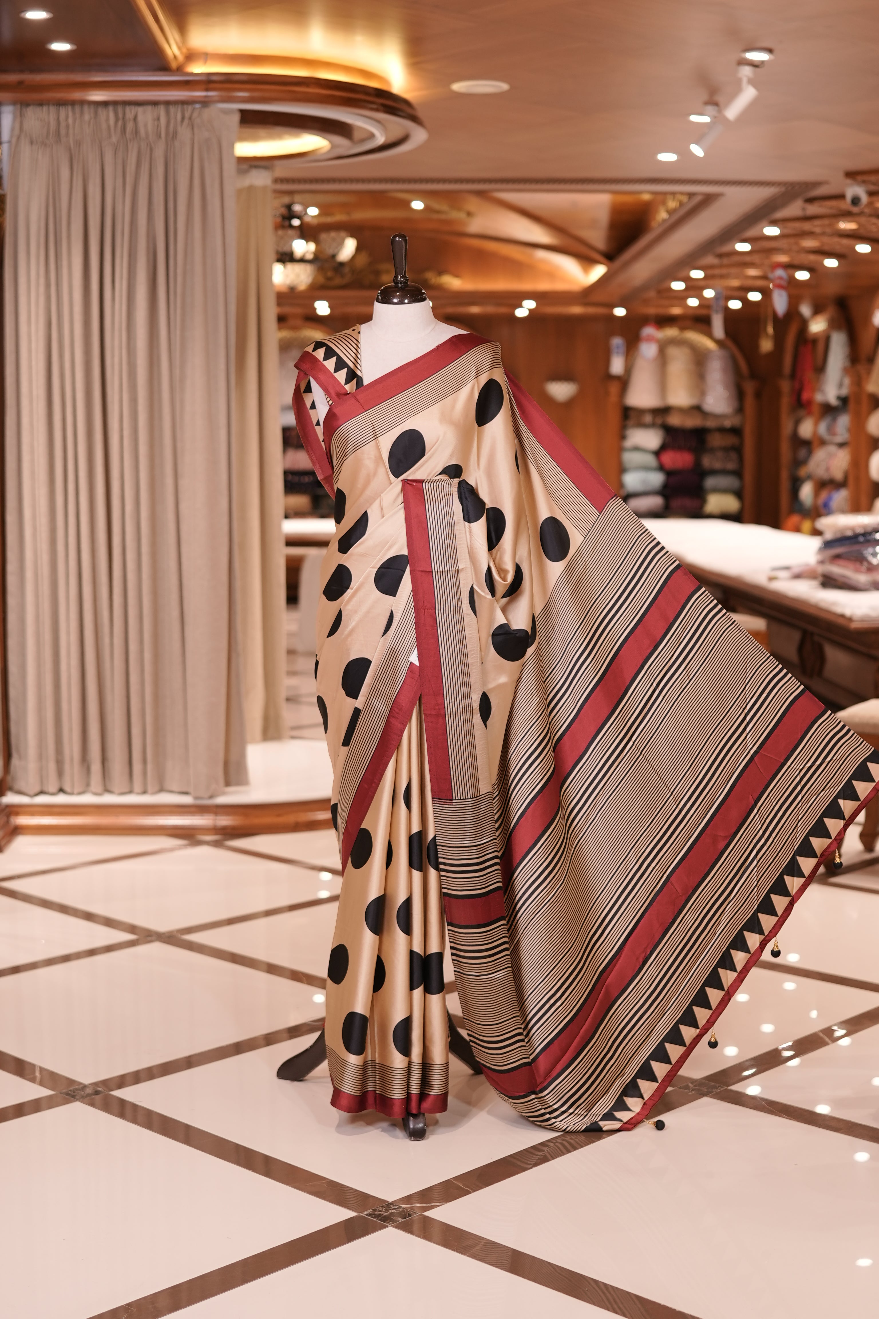 Cream colour semi modal saree featuring bold black polka dots and elegant striped detailing, finished with a contrasting maroon border and paired with a perfectly matching blouse