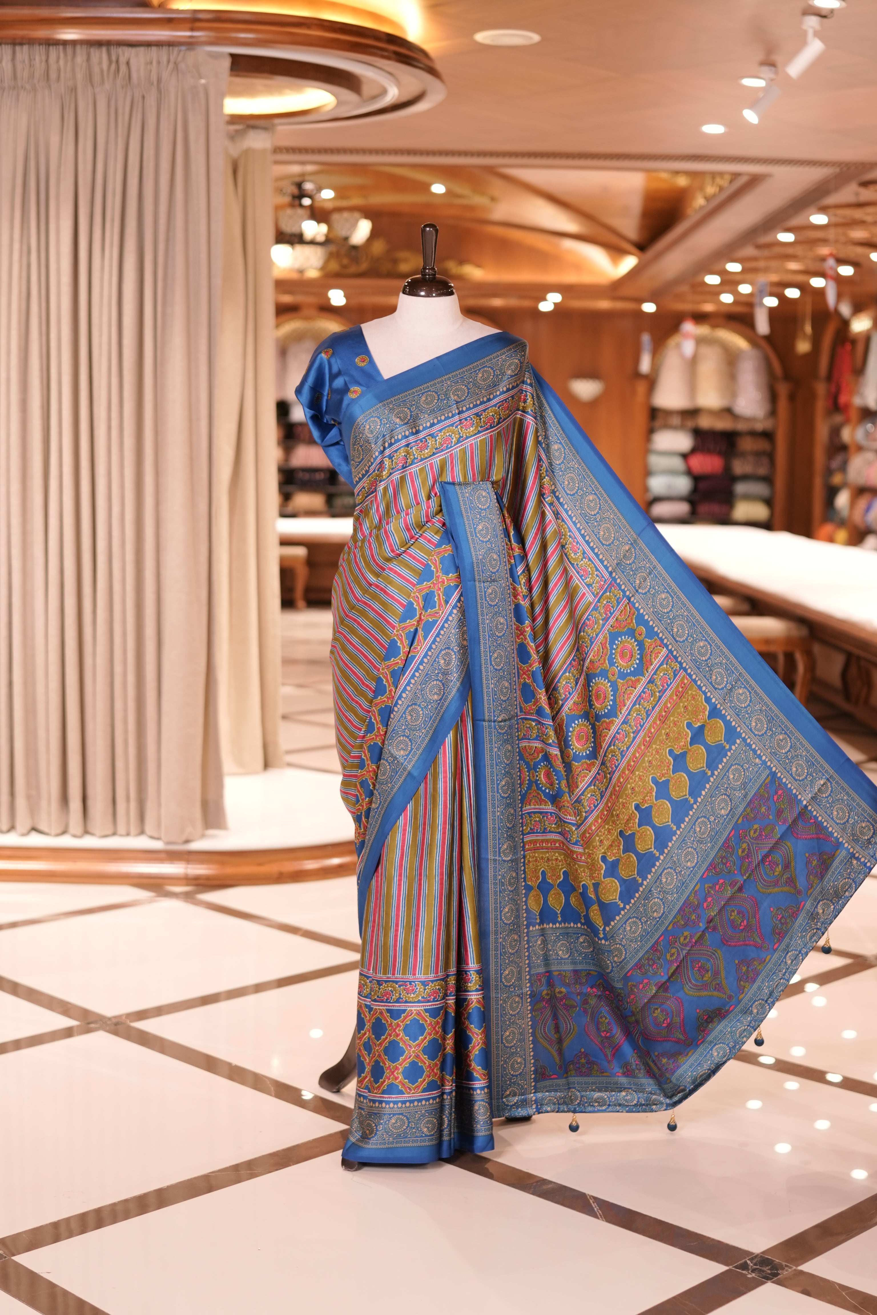 Blue and multi colour semi modal saree featuring vibrant vertical stripes and intricate geometric motifs, beautifully highlighted with an ornate traditional border, and paired with a perfectly matching blouse.