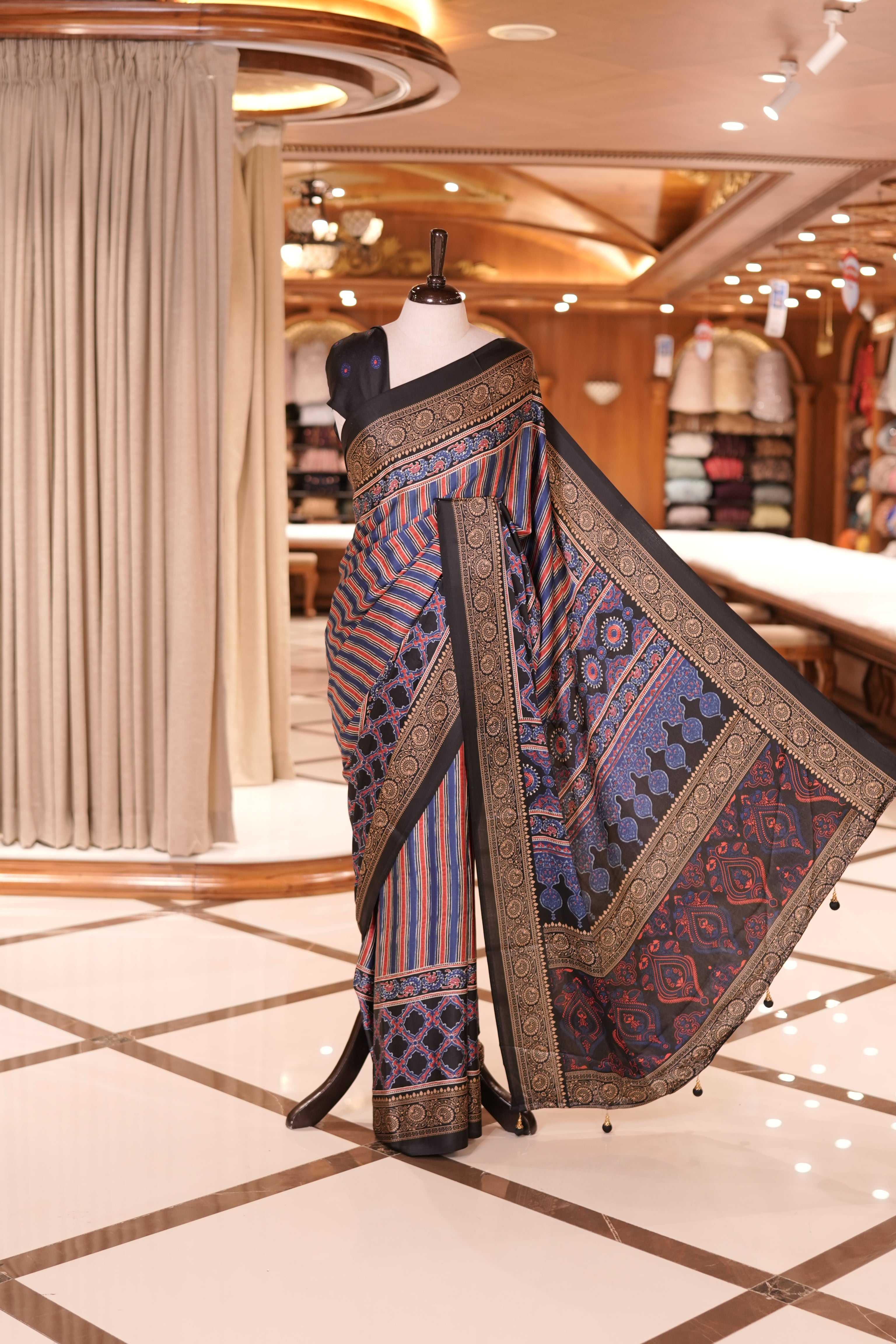 Black and multi colour semi modal saree featuring vibrant vertical stripes and intricate geometric motifs, beautifully highlighted with an ornate traditional border, and paired with a perfectly matching blouse.