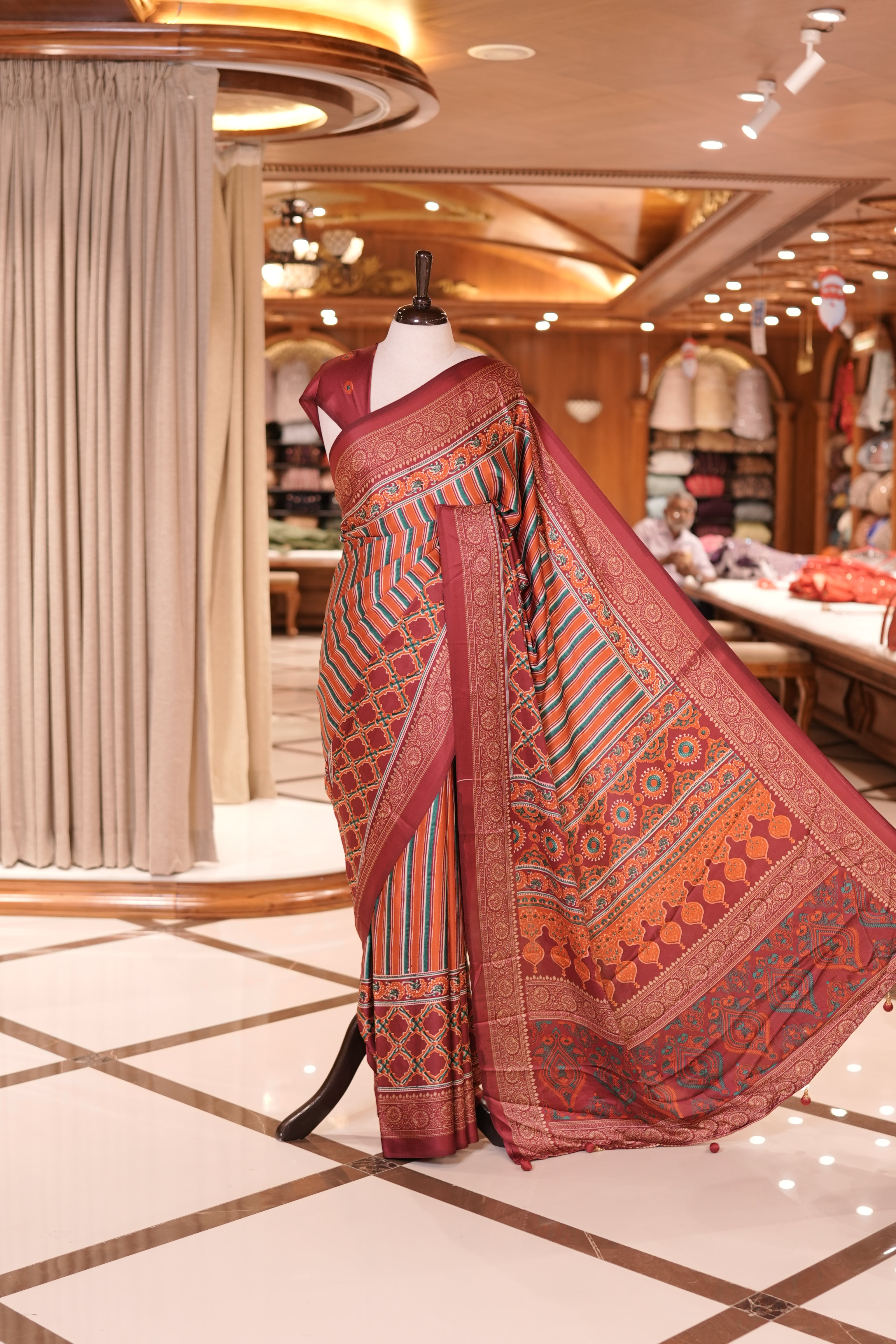 Red and multi colour semi modal saree featuring vibrant vertical stripes and intricate geometric motifs, beautifully highlighted with an ornate traditional border, and paired with a perfectly matching blouse.