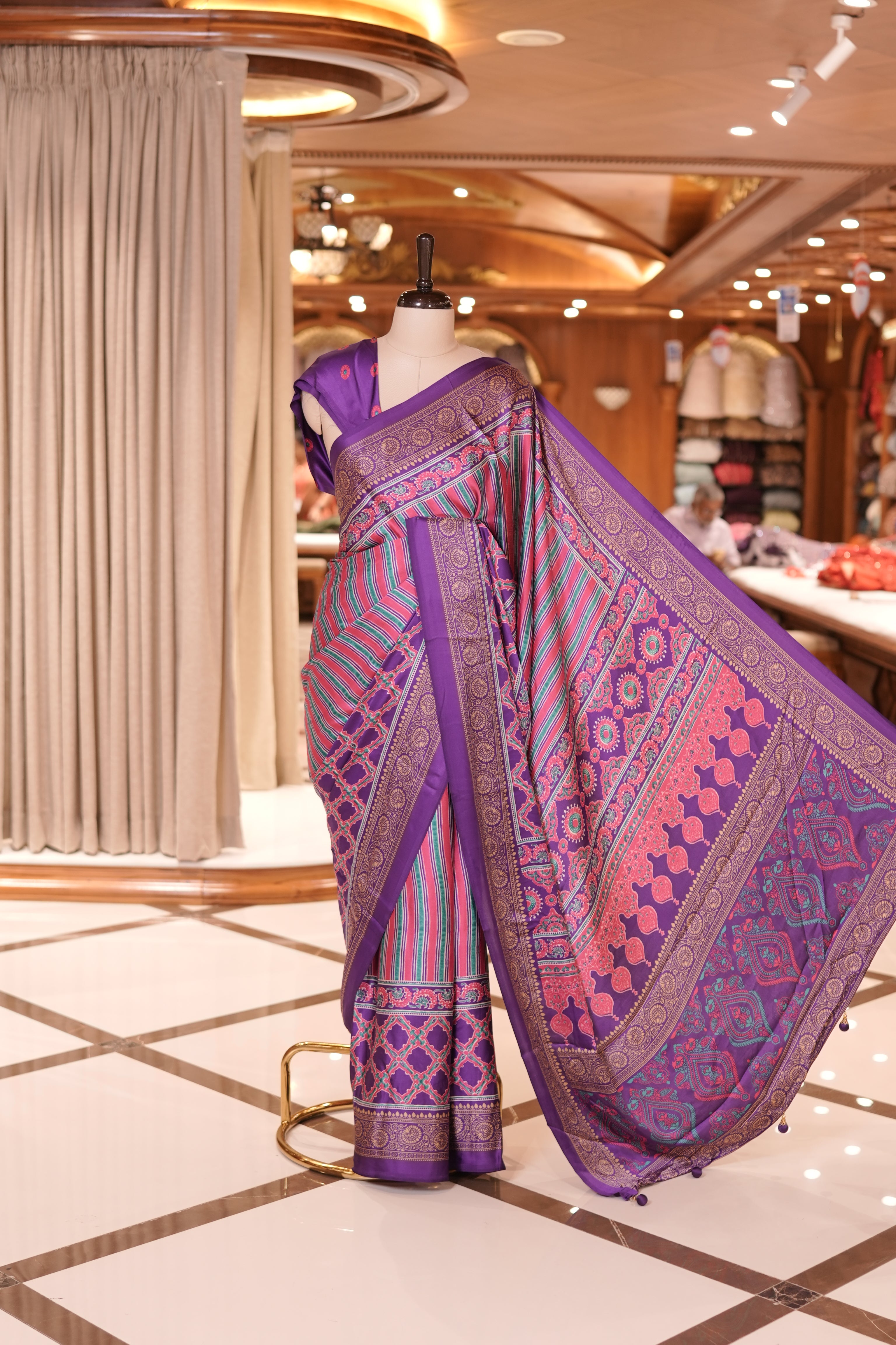 Violet and multi colour semi modal saree featuring vibrant vertical stripes and intricate geometric motifs, beautifully highlighted with an ornate traditional border, and paired with a perfectly matching blouse.