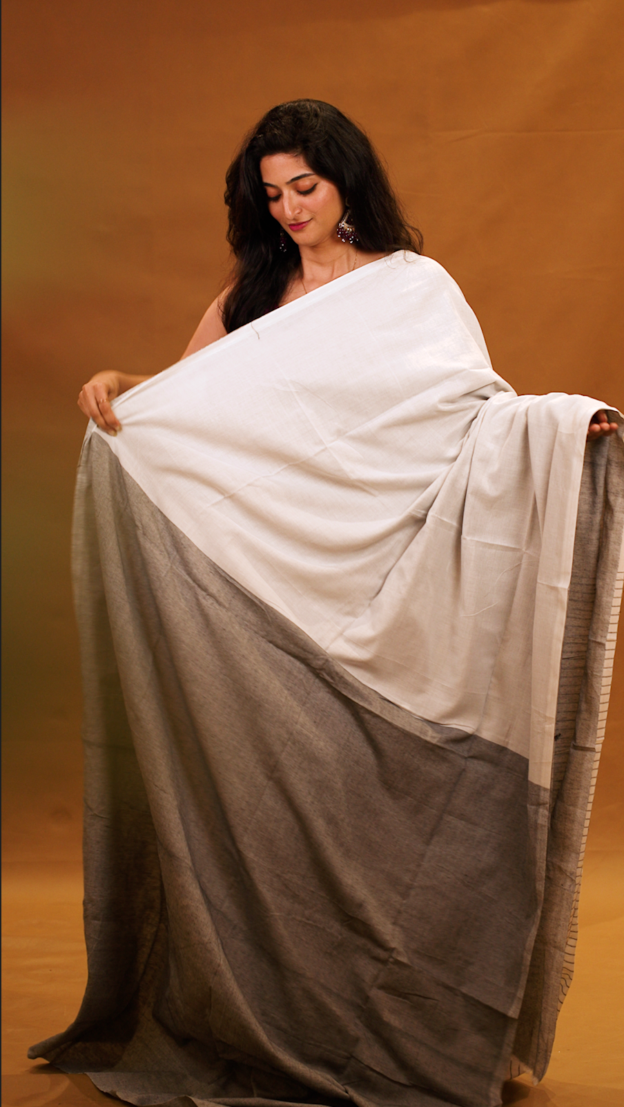 Black colour Mul Cotton saree featuring a half and half patterned body, highlighted by a contrast border and striped pallu, paired with a matching blouse piece.