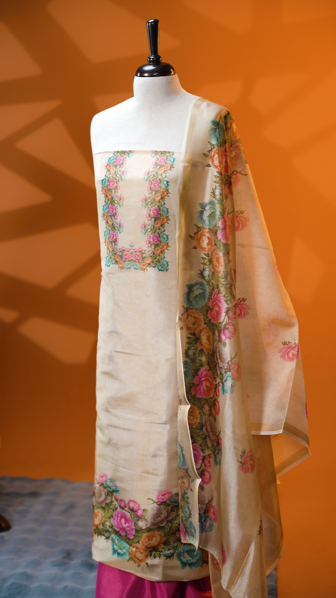 Light gold colour Tissue Salwar material featuring Peach, pink & aqua colour floral print, paired with Dupatta with same print & Golden line detailed border and santoon bottom material.
