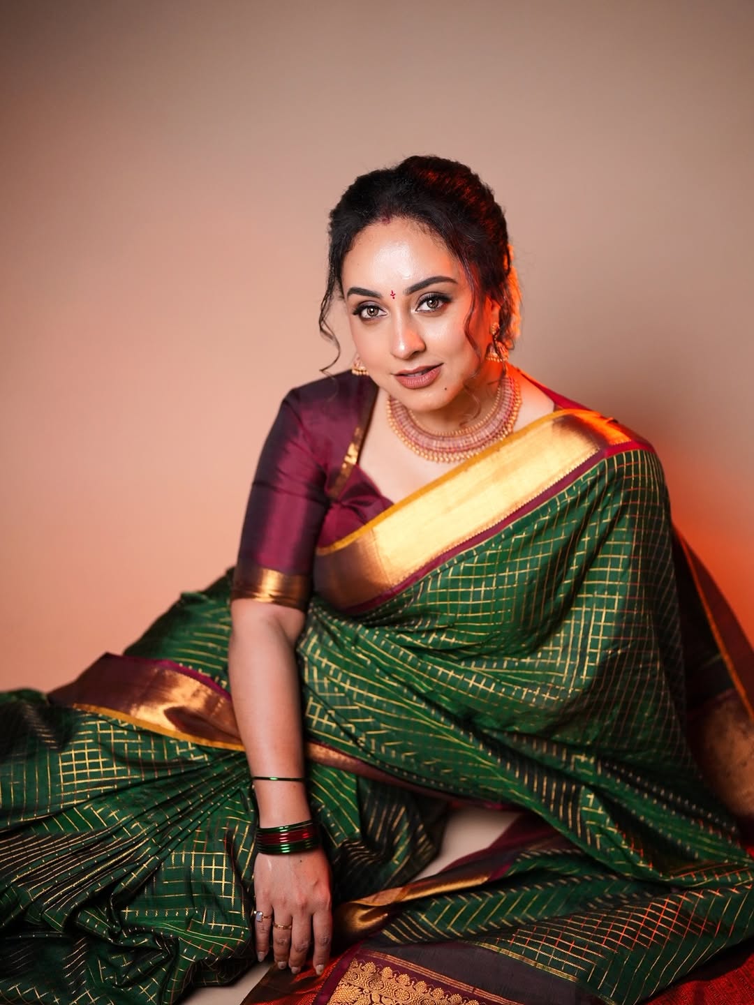 Bottle green and maroon Kancheepuram silk saree adorned with zari checks on the body, traditional bavanji border, mustard-maroon edge piping, and a contrasting jacquard zari pallu, paired with a matching maroon blouse