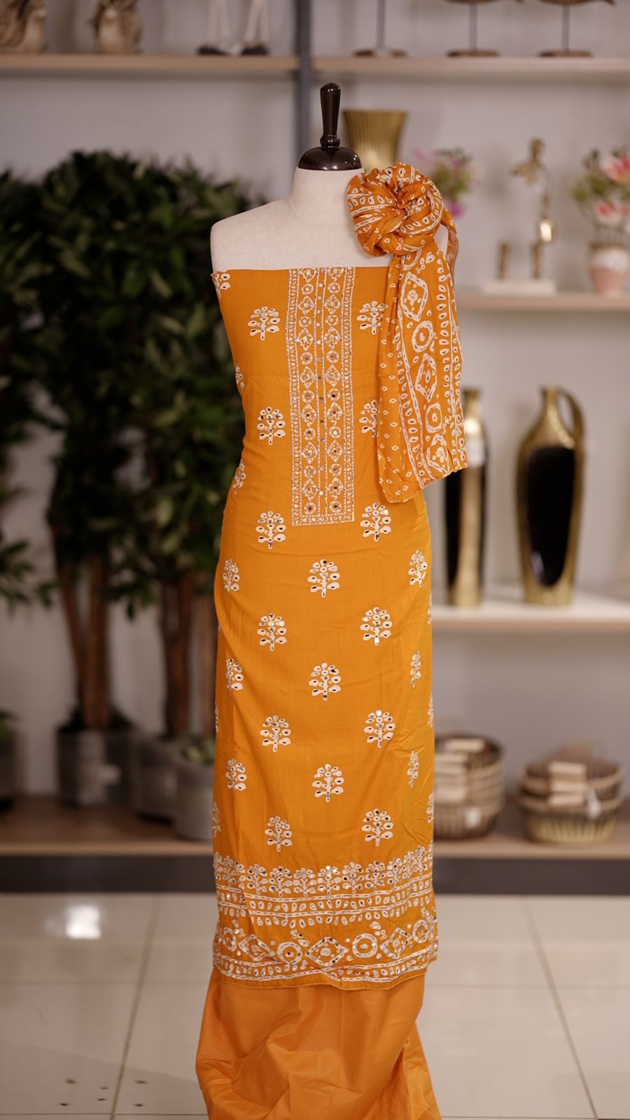 Mustard Yellow colour cotton churidhar material featuring floral prints with delicate mirror design on the top, paired with a matching bottom and printed dupatta