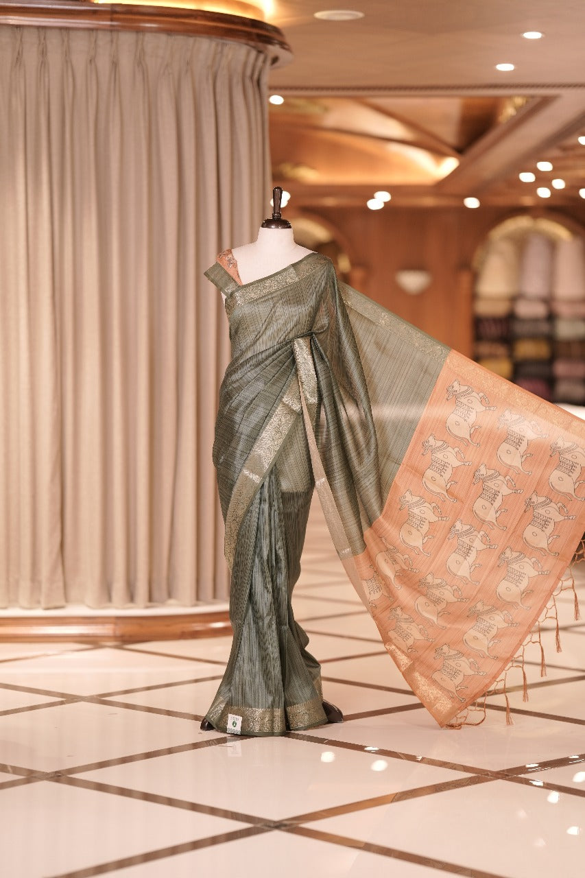 Green & mustard yellow colour Dolla silk saree featuring a striped body with a matching golden zari border, The pallu showcases exquisite Kalamkari prints, complemented by a contrast printed blouse.