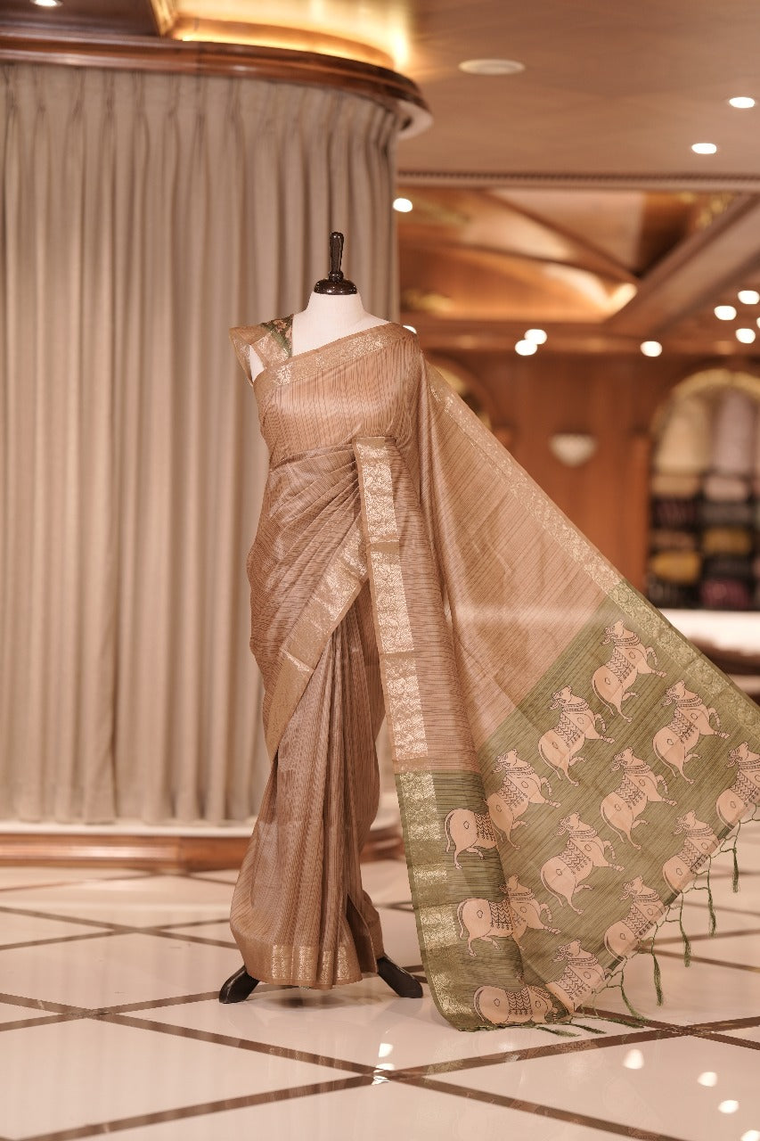 Chikku & green colour Dolla silk saree featuring a striped body with a matching golden zari border, The pallu showcases exquisite Kalamkari prints, complemented by a contrast printed blouse.