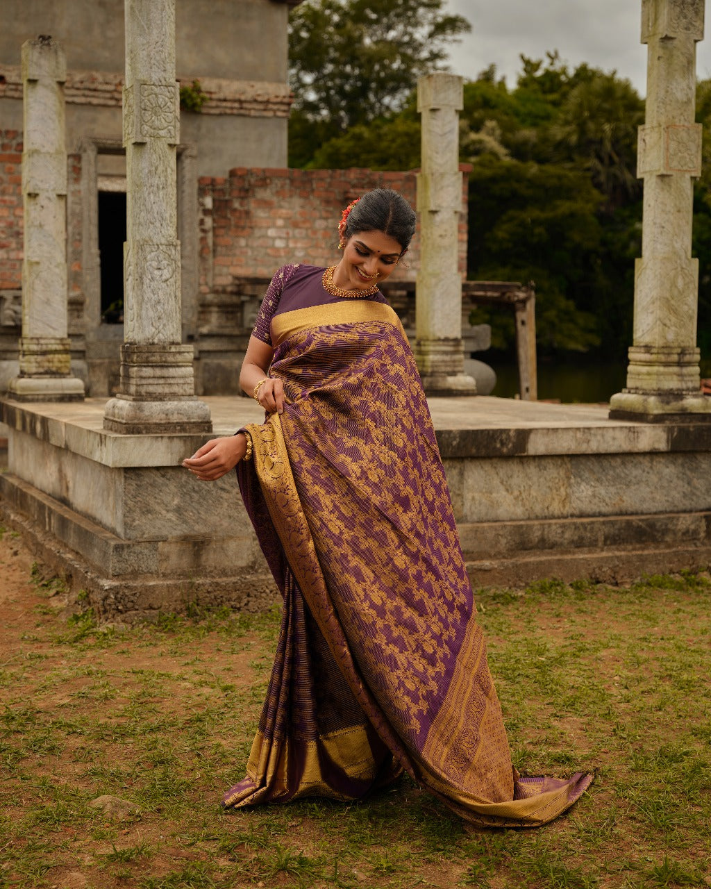 Dark purple colour Samudrika Pattu saree featuring traditional Kodi Malar motifs with peacock, elephant, and simham zari weaving, complemented by an elegant Annam zari pettu border and paired with a matching blouse piece.
