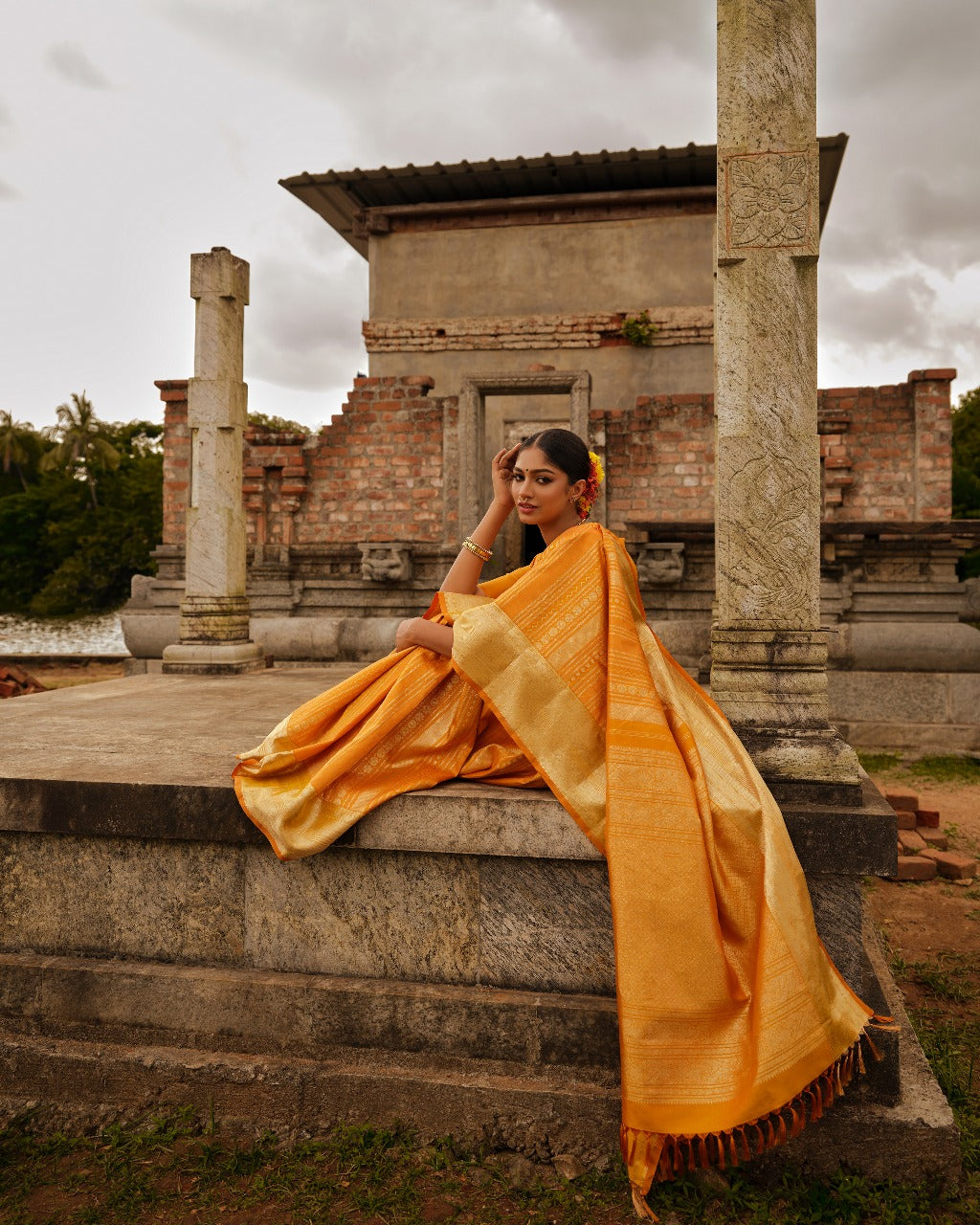 Golden mustard colour Samudrika wedding saree featuring elegant vertical geometric jacquard designs woven in antique silver and copper zari, complemented by a traditional zari pettu border and paired with a matching blouse piece.