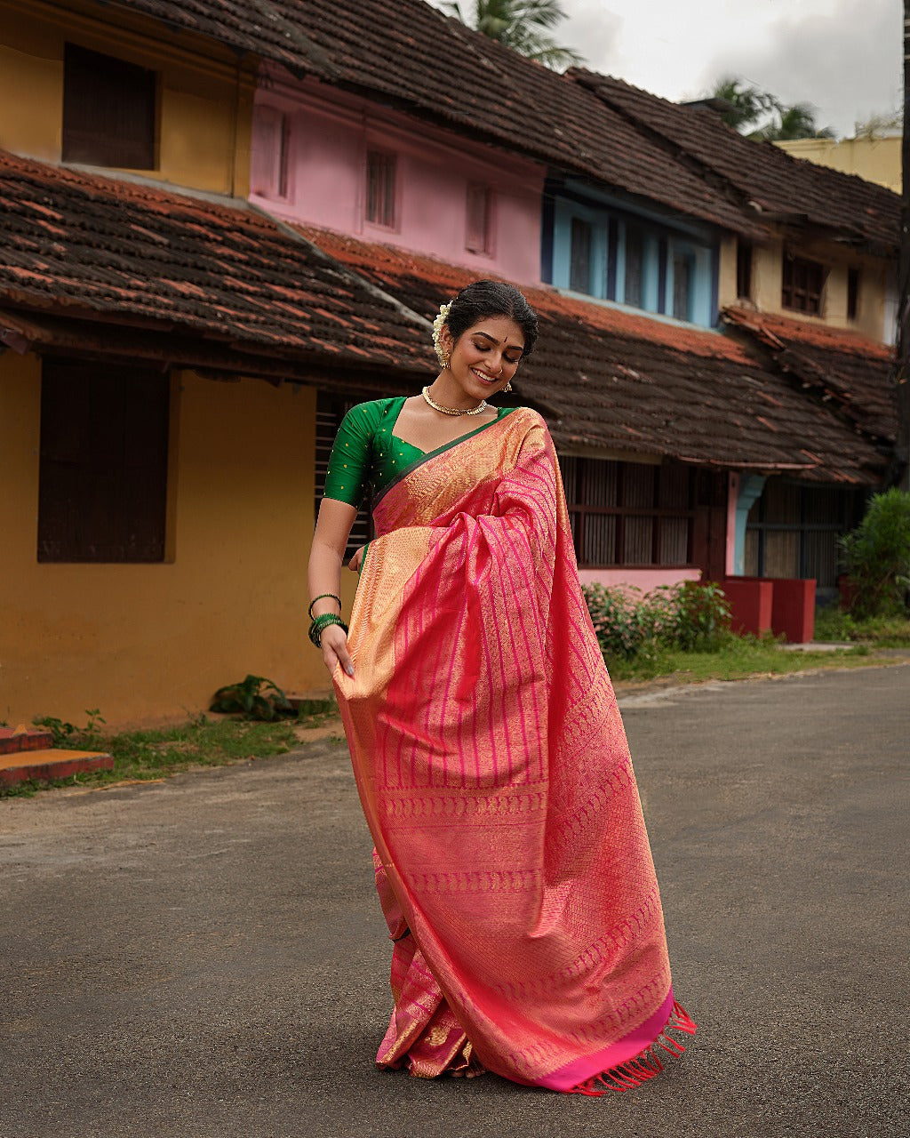 Rani pink colour Samudrika Pattu saree featuring elegant horizontal zari jacquard weaving, complemented by a traditional gold zari border accentuated with green piping for a striking finish, and paired with a matching blouse piece.