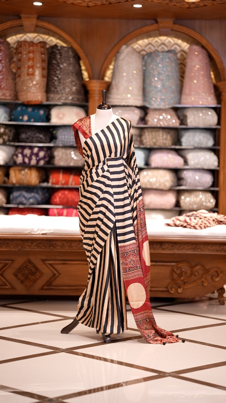 Cream and black striped Semi modal silksaree highlighted with a rich maroon pallu featuring artistic motifs, paired with a matching blouse