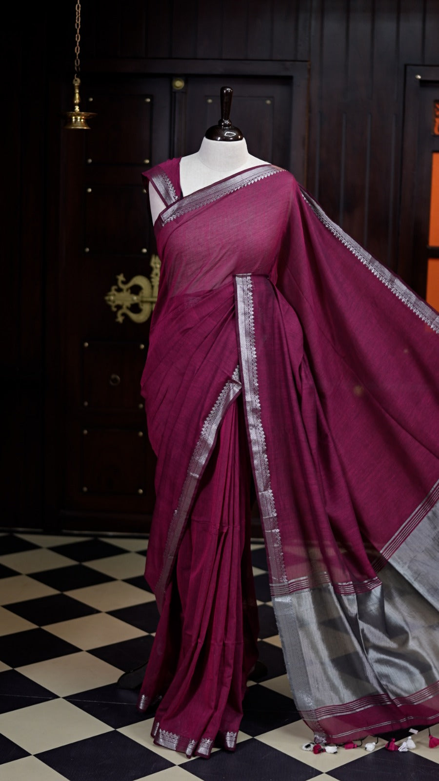 Deep Wine colour saree with a soft, airy drape, accentuated by delicate silver woven borders and a subtle striped pallu, paired with a matching blouse.