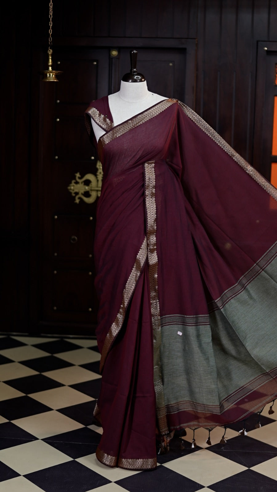 Deep Maroon colour saree with a soft, airy drape, accentuated by delicate copper woven borders and a subtle striped pallu, paired with a matching blouse.