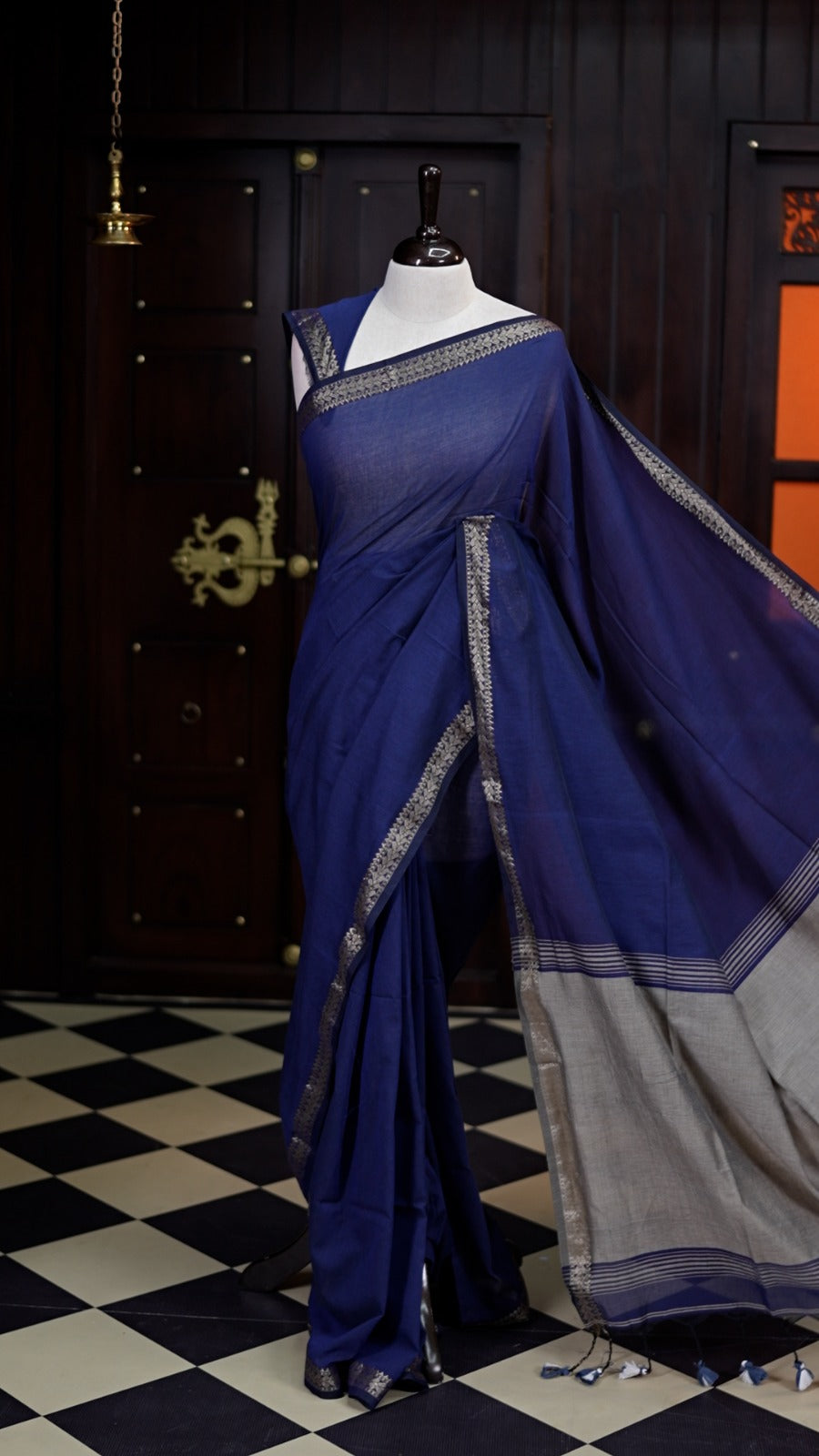 Deep navy blue saree with a soft, airy drape, accentuated by delicate silver woven borders and a subtle striped pallu, paired with a matching blouse.