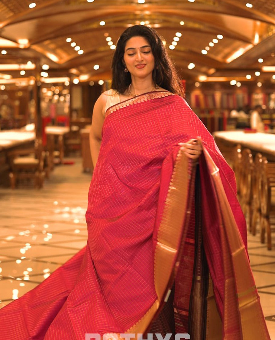 Magenta colour semi banaras lichi silk saree featuring checked patterned body, complemented by gold zari border, paired with matching blouse piece.