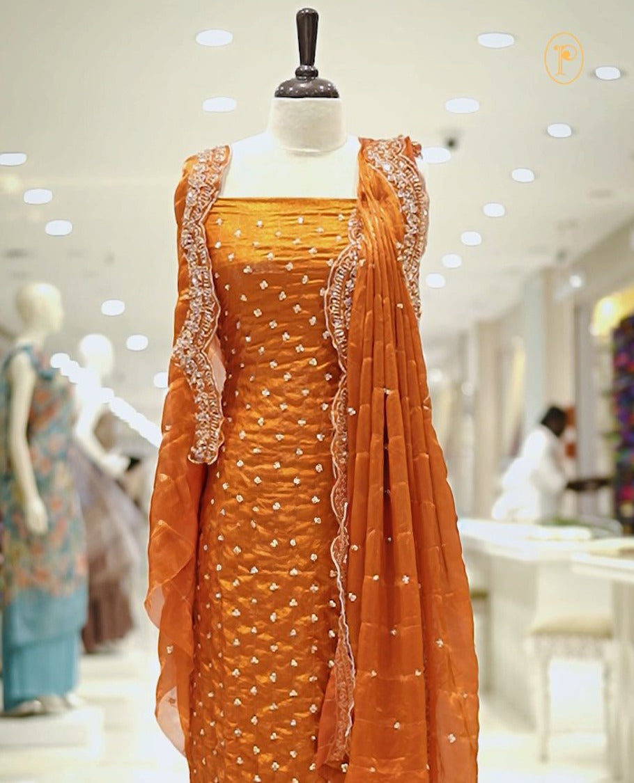Orange colour Fenty silk salwar material highlighting gold sequins on body and scalp design on border, matching dupatta with scalp design, paired with matching bottom.