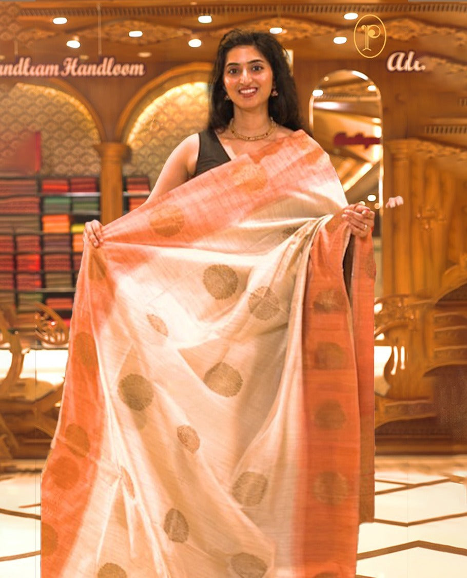 Cream colour Semi Jute saree featuring bold zari motifs across the body with a rust orange colour parallel panel border, paired with a running blouse piece.