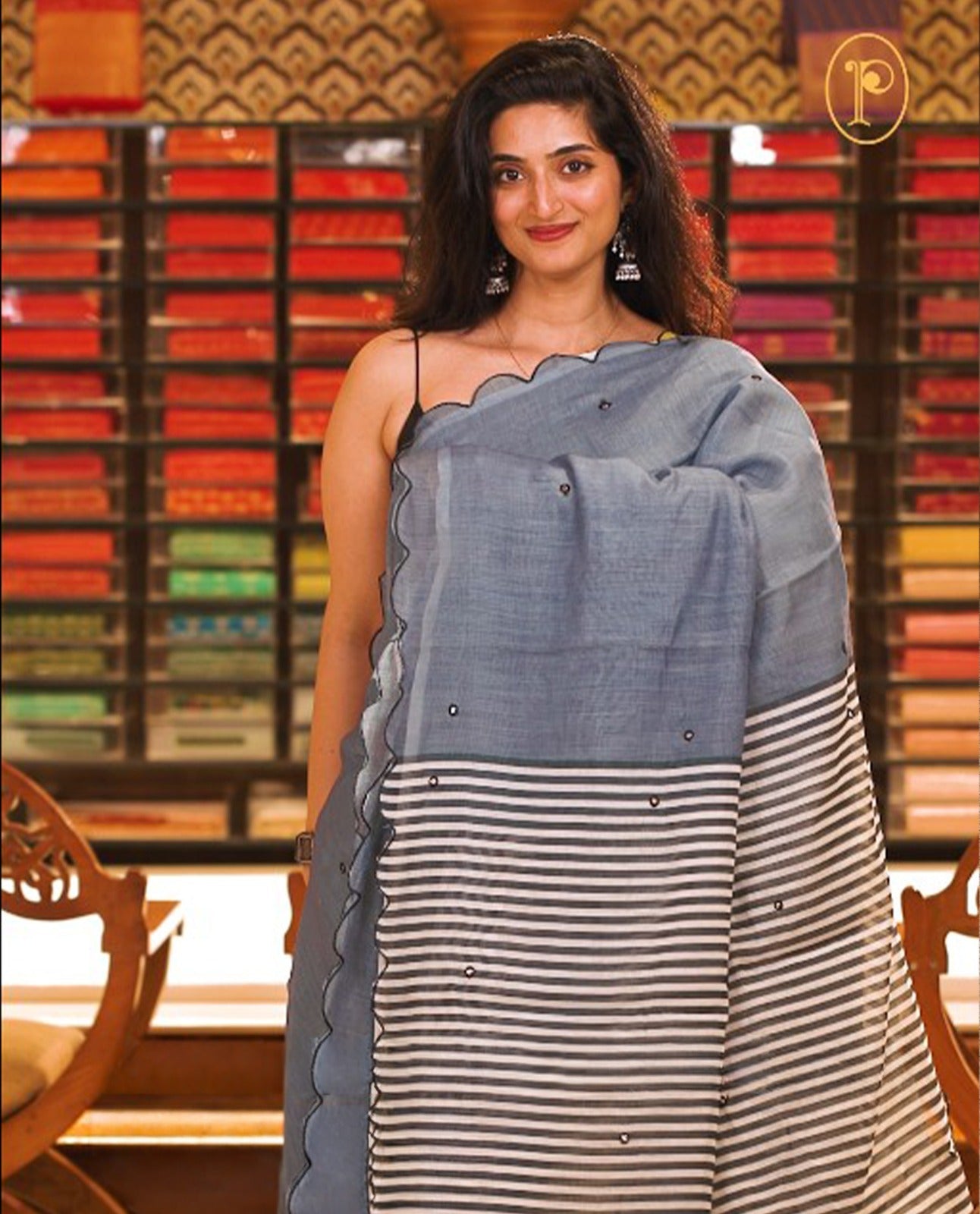 Grey colour Semi Linen saree featuring mirror work with intricate thread detailing, enhanced by a stylish scallop border. Comes without a blouse piece.