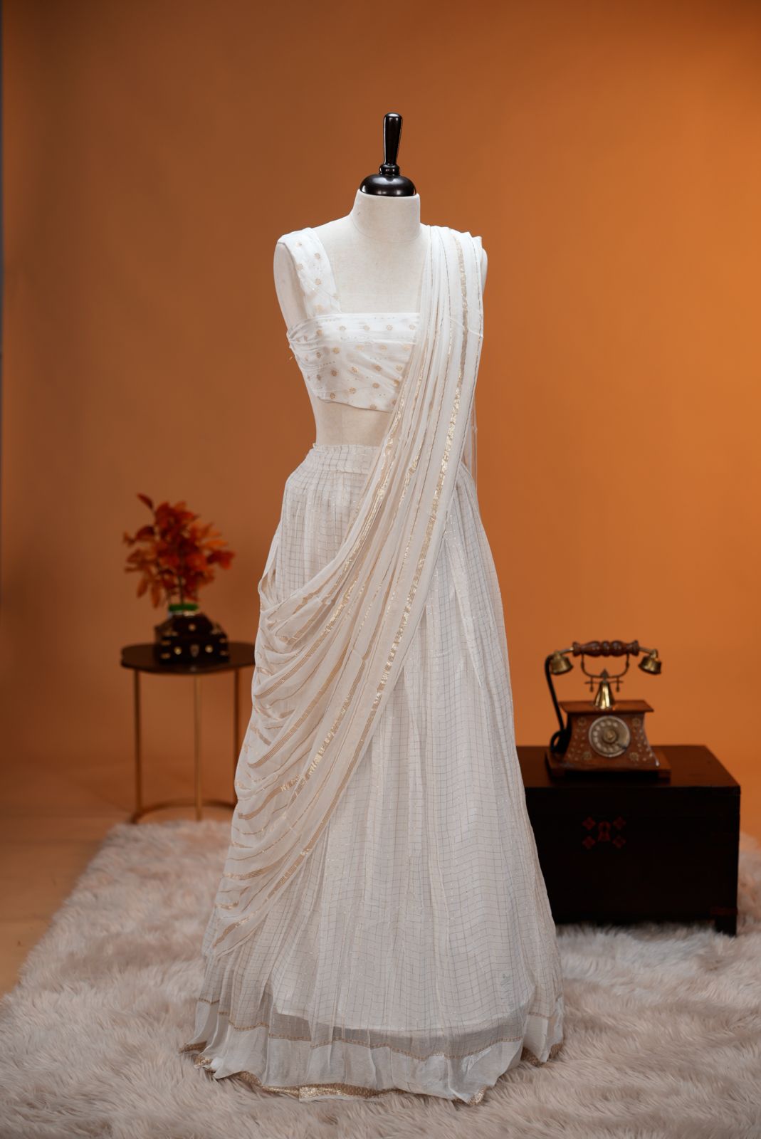 White colour Georgette Dhavani material featuring white skirt with Check pattern & border, Small floral work on blouse piece, same colour dupatta with strips.