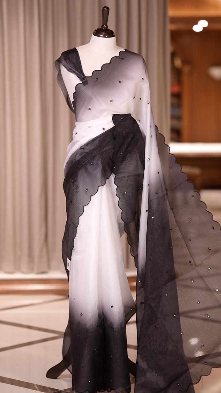 Black colour Doriya check cotton saree with soft sequins work on the body, elegant embroidery scallop border, and a simple pallu & Comes with a matching plain blouse piece.