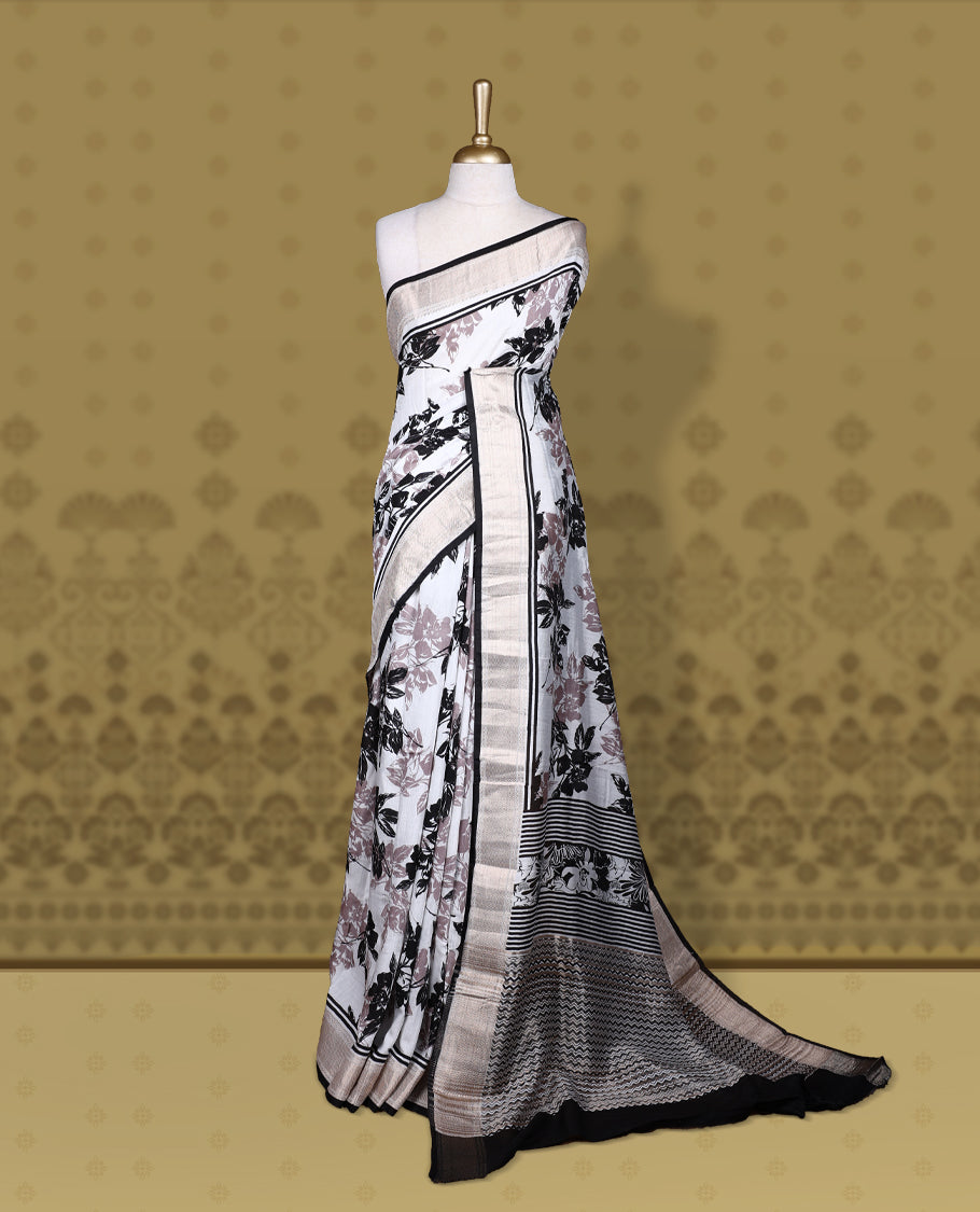 White colour saree with black and mauve floral prints, featuring a contrast zari border and detailed pallu & Comes with a matching blouse piece.