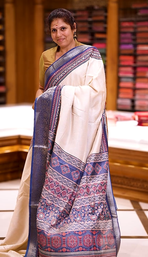Beige Dolla silk saree featuring antique zari stripes across the body,  adorned with a striking Ajrak and Traditional blue colour border, ajrak  printed