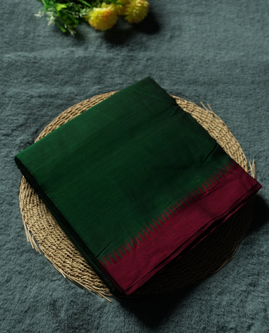 Dark Green colour Narayanapattu cotton saree featuring a self coloured body, maroon coloured zari pattern border and maroon striped colour pallu, pairing a matching blouse piece.