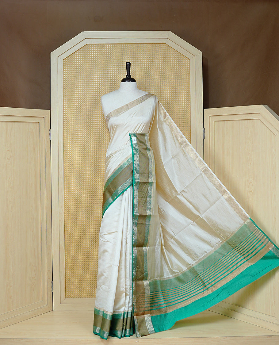 Cream colour semi Tussar silk saree featuring Elegant body, Complemented by contrast Aqua Green with rich zari detailed for onam special, paired with contrast Blouse for Festive look.