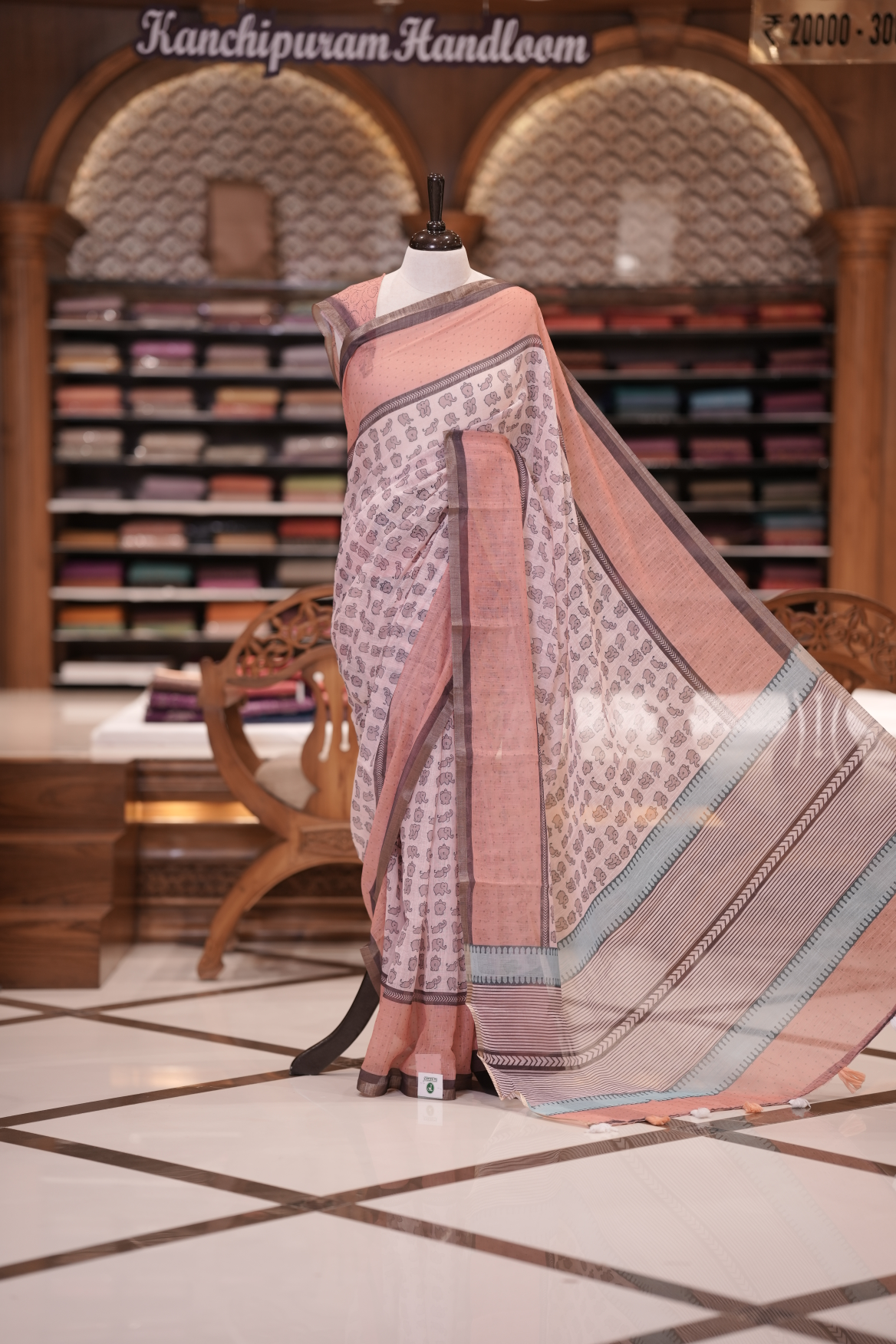 Peach colour soft linen saree adorned with cute elephant prints all over the body, complemented by a contrast woven border and paired with a matching printed blouse piece