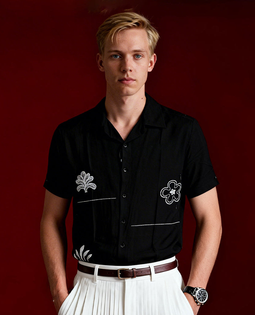 Black colour shirt featuring elegant white embroidery motifs on the body, Designed with a classic shirt collar and short sleeves, it blends contemporary style with subtle detailing.
